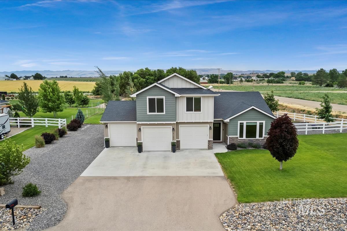 View of front of property featuring concrete driveway, an attached garage, board and batten siding, and a view of rural / pastoral area