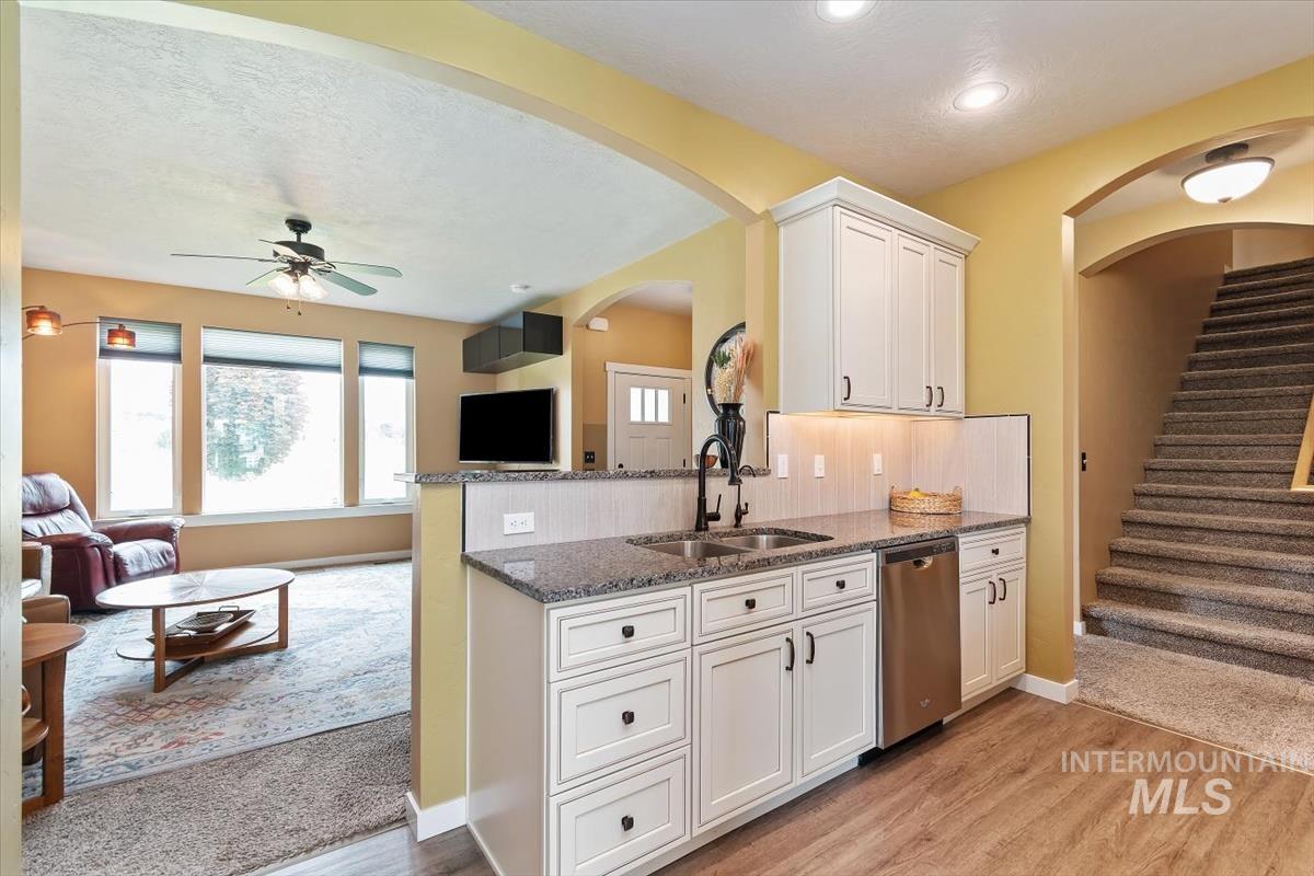 Kitchen featuring dishwasher, dark stone countertops, open floor plan, a ceiling fan, and recessed lighting