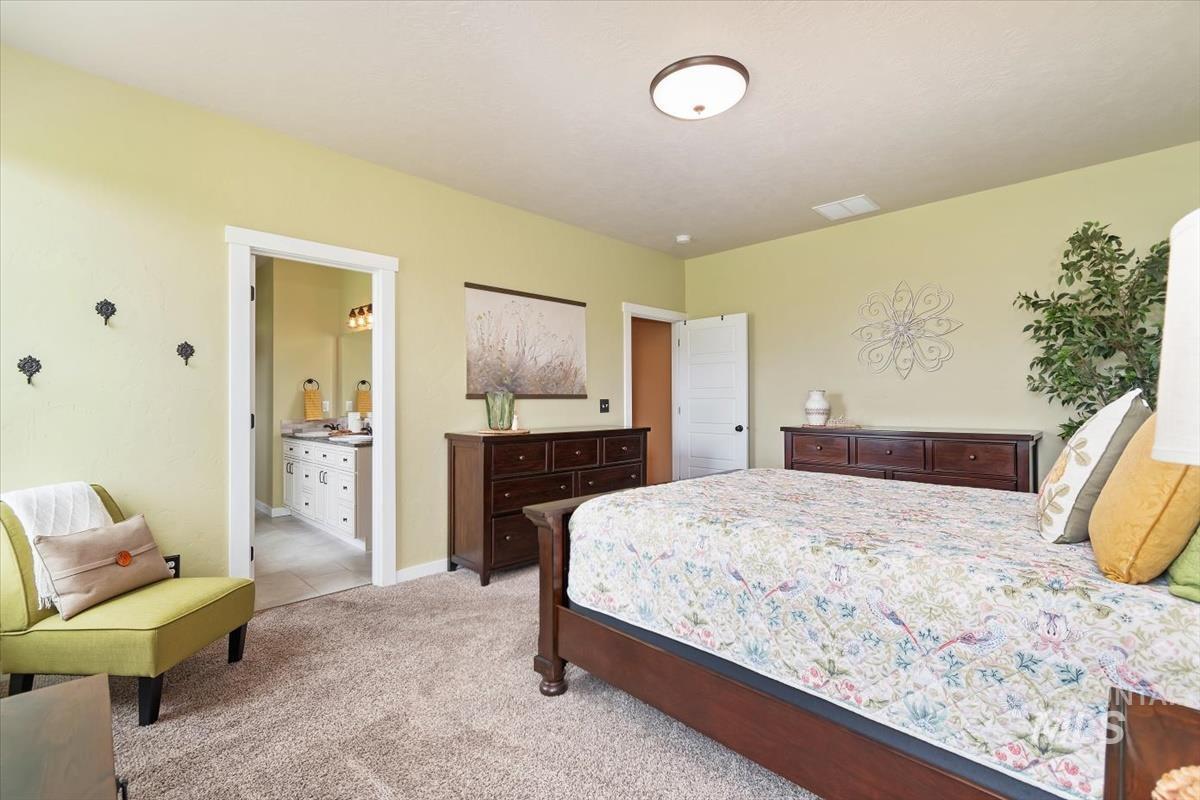 Bedroom with light carpet and connected bathroom