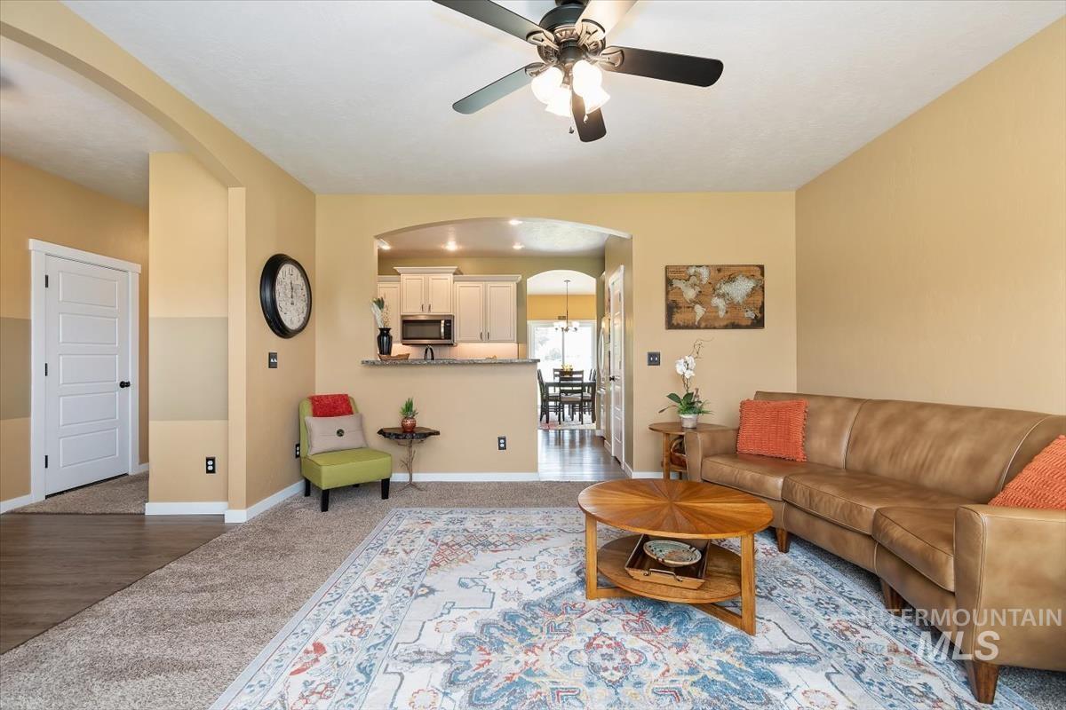 Living area with arched walkways, a ceiling fan, and carpet