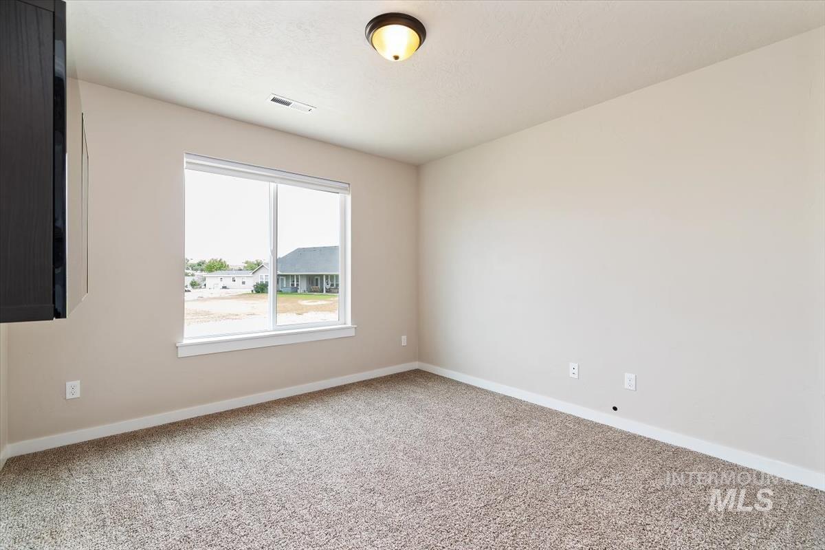 Carpeted spare room featuring baseboards