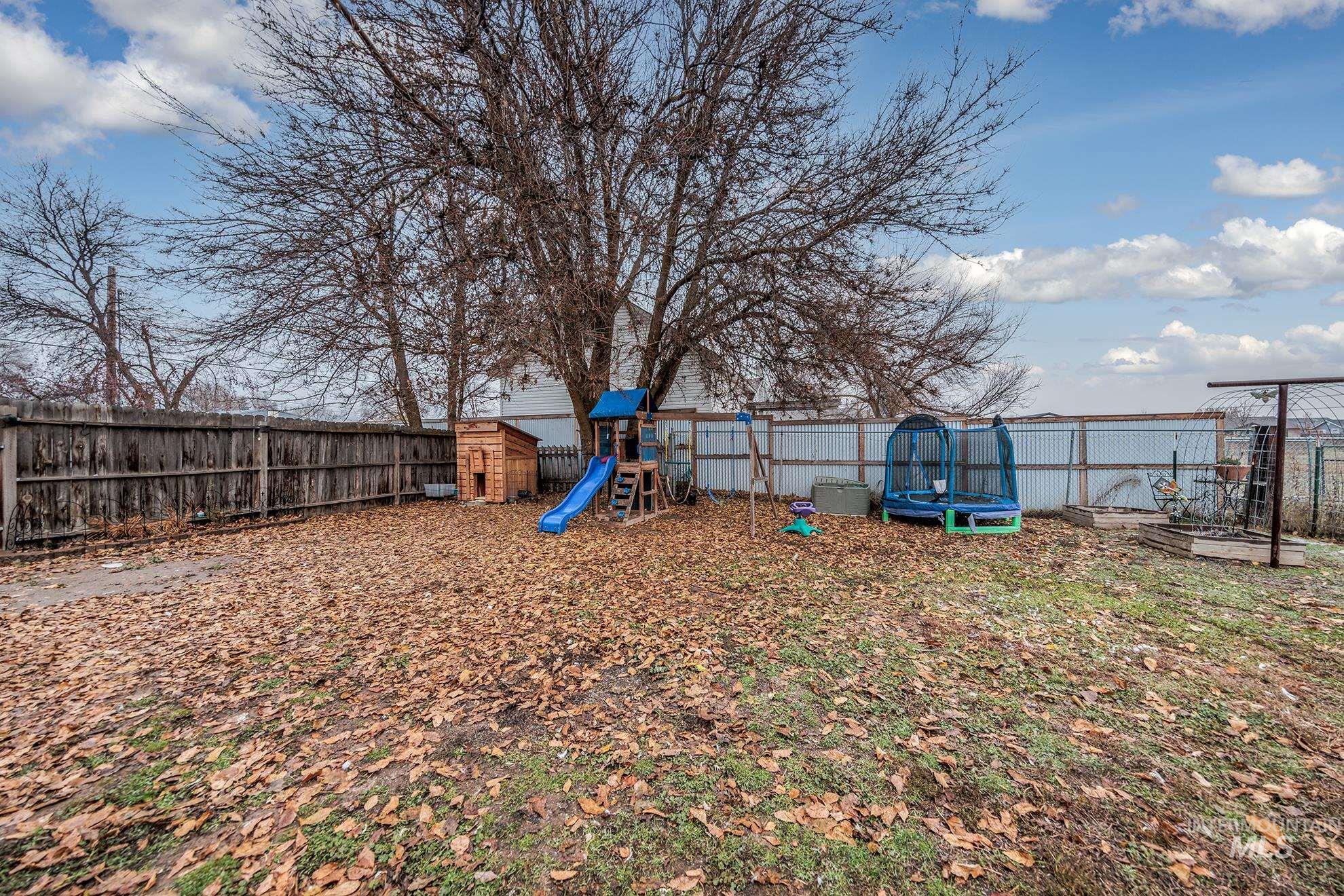 Fenced backyard with a trampoline and a playground