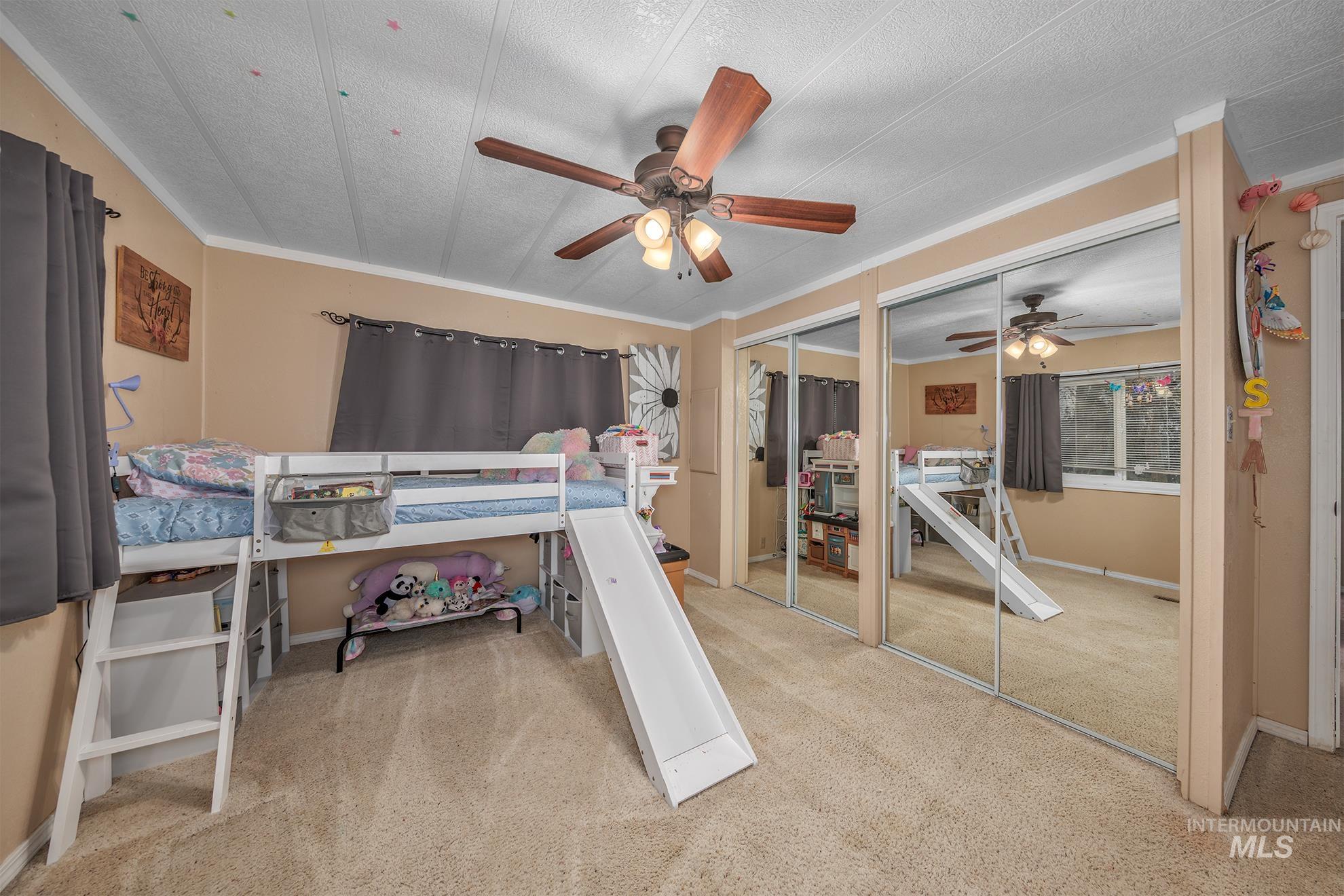 Bedroom with multiple closets, light colored carpet, crown molding, and ceiling fan