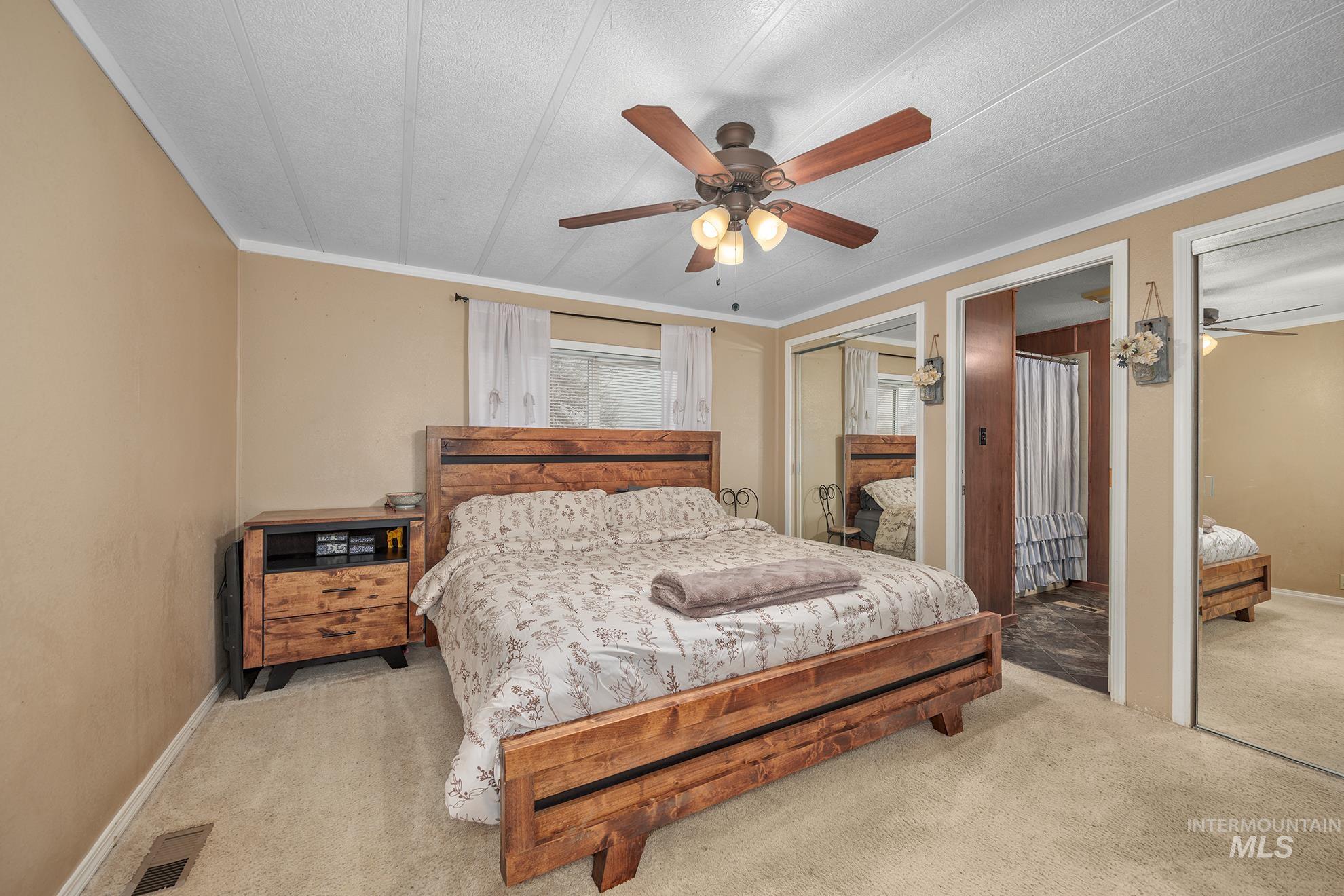 Bedroom featuring two closets, carpet, a ceiling fan, and crown molding