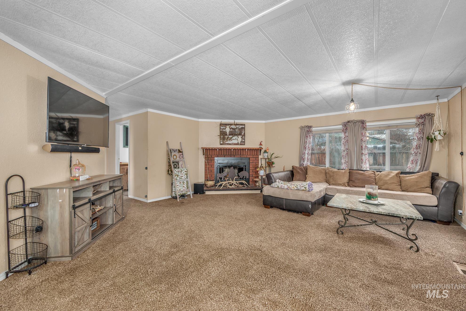 Carpeted living room featuring crown molding and a fireplace