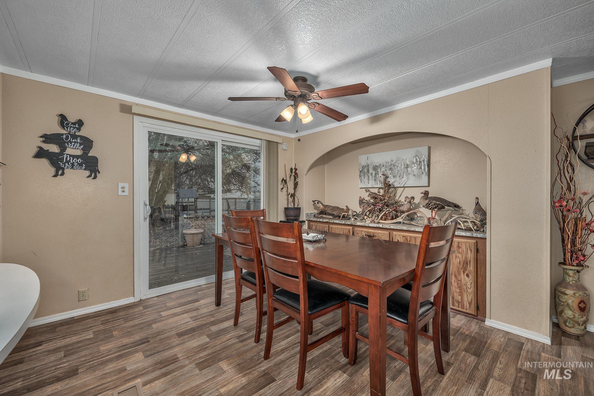 Dining area featuring crown molding, wood finished floors, a ceiling fan, and a textured ceiling