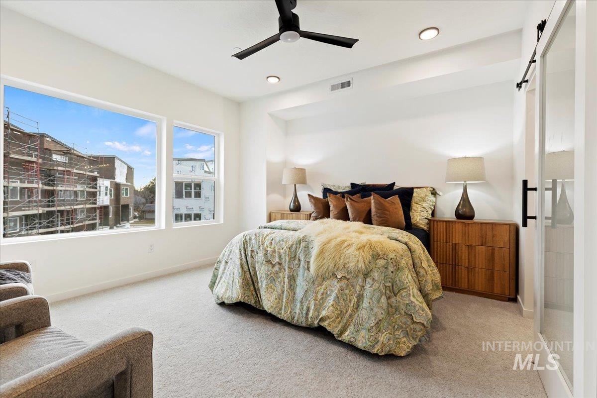 Carpeted bedroom with a barn door, a ceiling fan, and recessed lighting