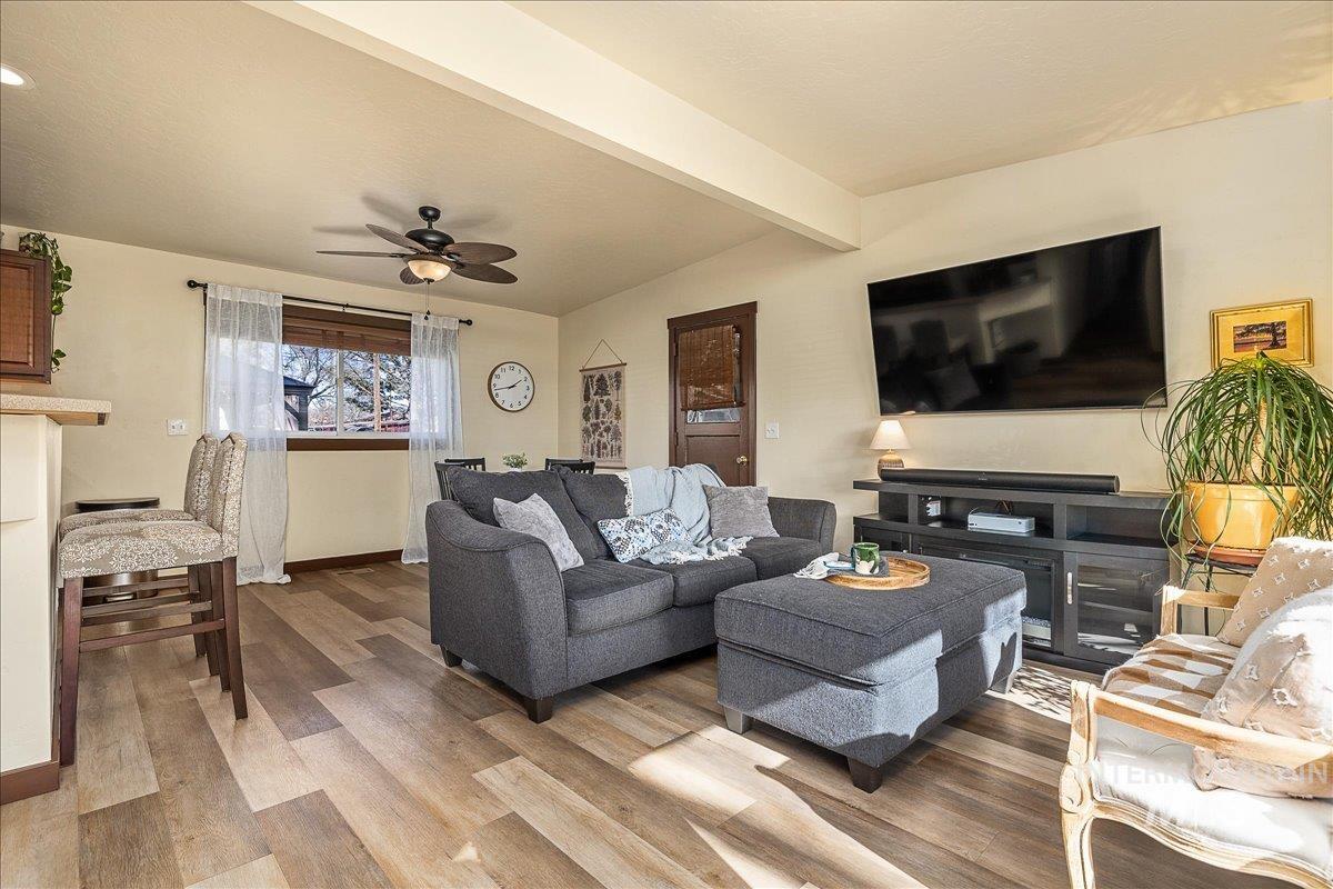 Living room featuring a ceiling fan, wood finished floors, and beamed ceiling