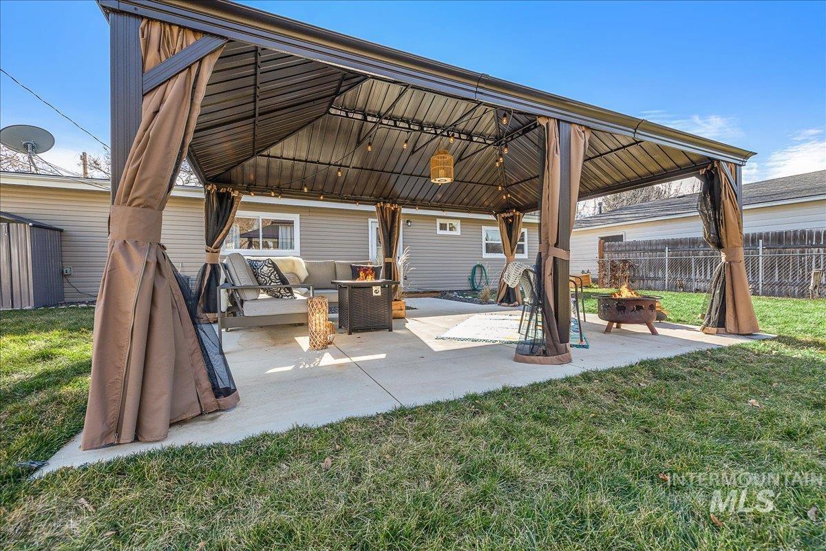 Rear view of property with a patio, an outdoor living space with a fire pit, and a gazebo