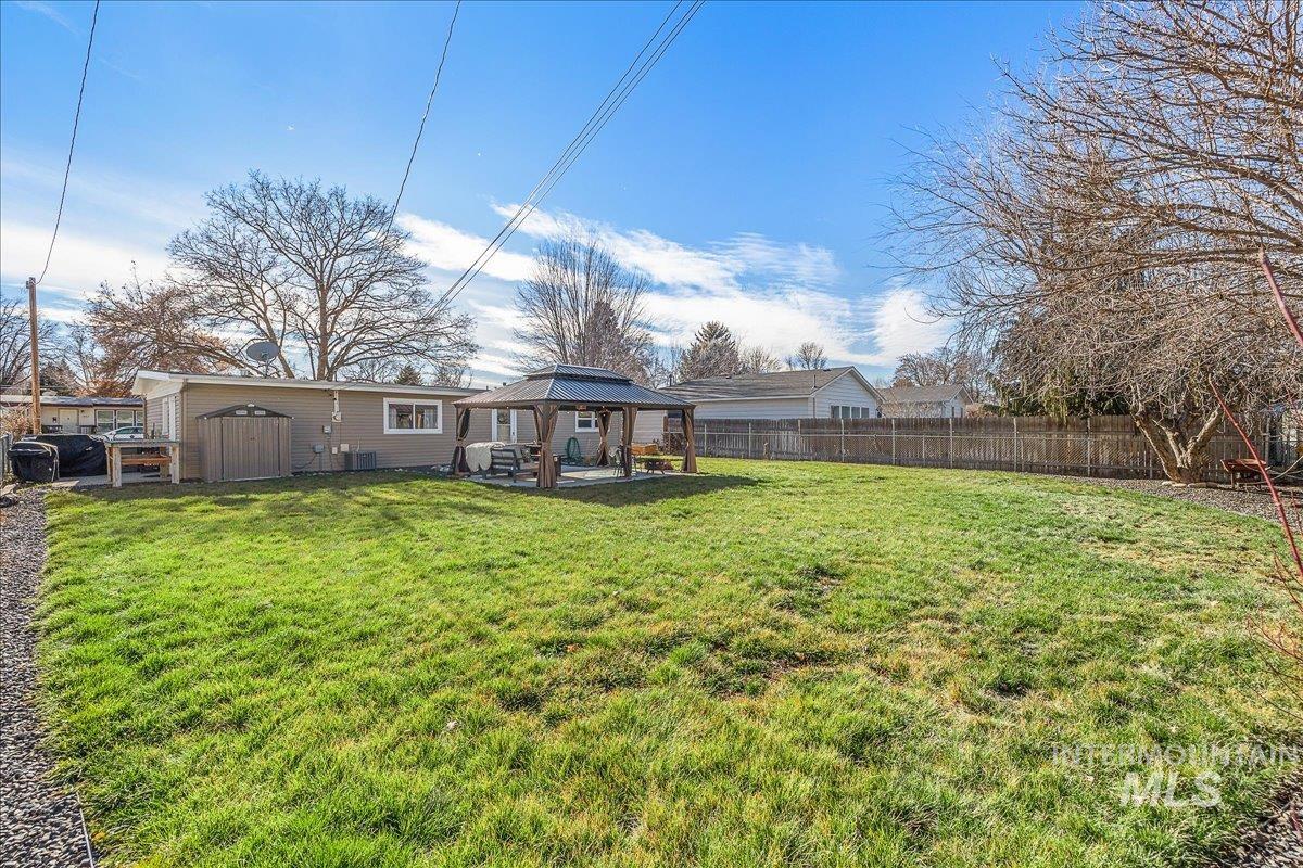 Rear view of house with a gazebo, a fenced backyard, a storage unit, and a patio