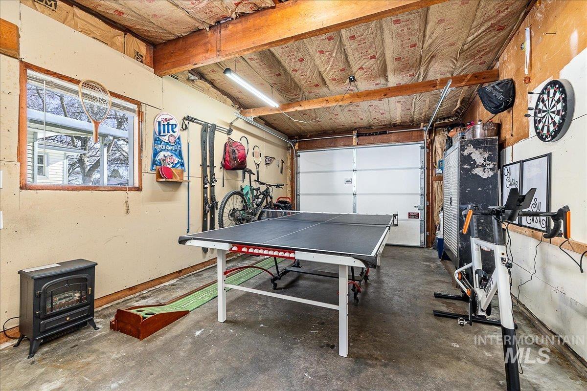 Game room featuring a wood stove, concrete floors, and a garage