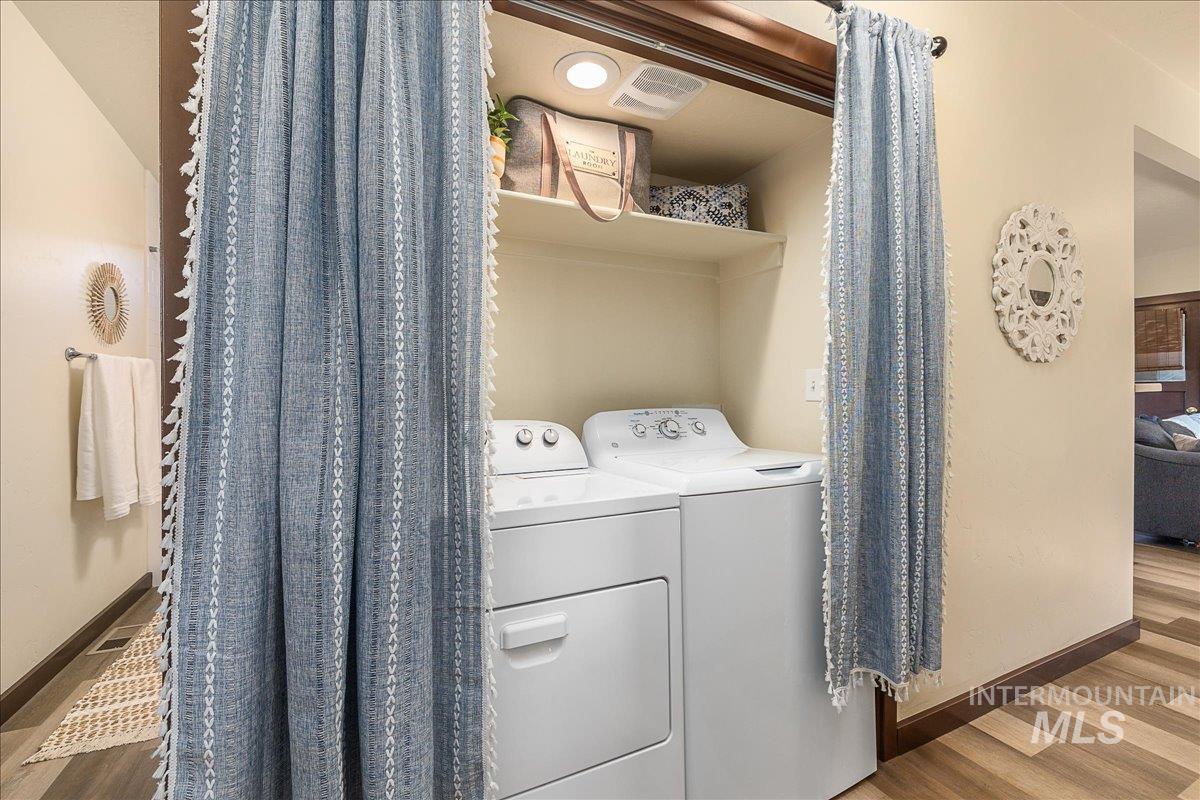 Laundry area with wood finished floors and washer and dryer