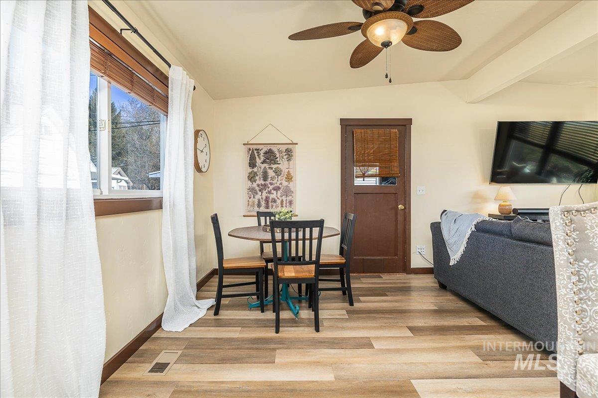 Dining area with light wood-style flooring, lofted ceiling, and a ceiling fan