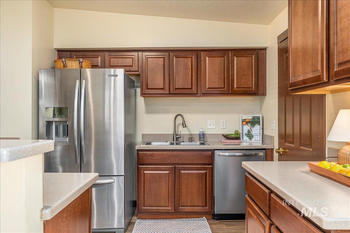 Kitchen with stainless steel appliances, light countertops, wood finish cabinetry, and dark wood finished floors