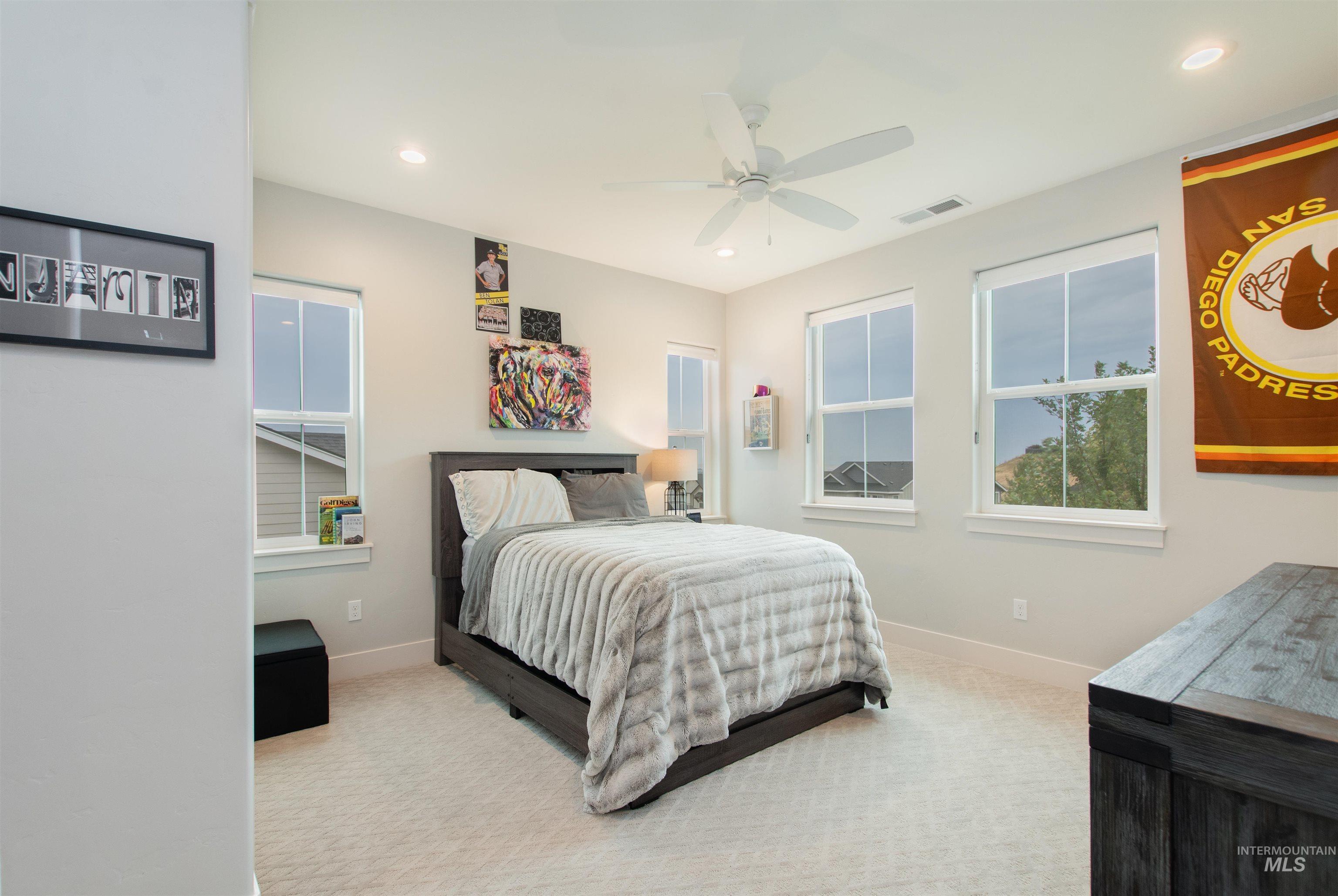 Carpeted bedroom with a ceiling fan and recessed lighting