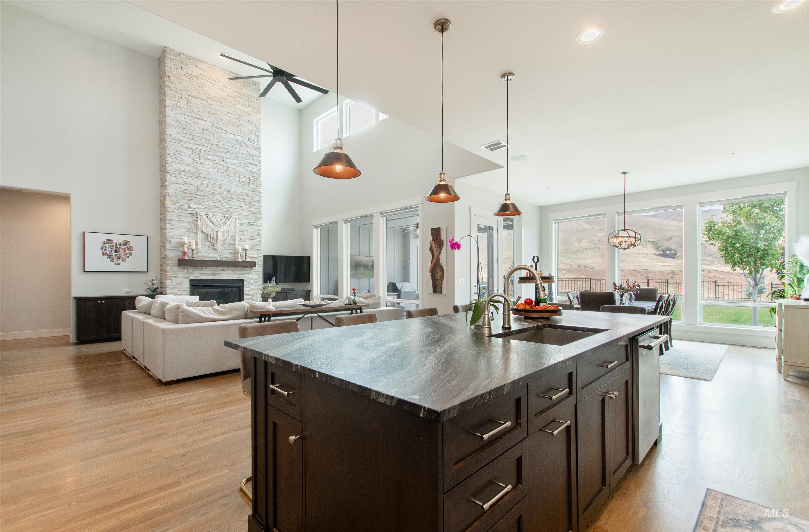 Kitchen featuring dark brown cabinets, a fireplace, decorative light fixtures, open floor plan, and light wood-style floors