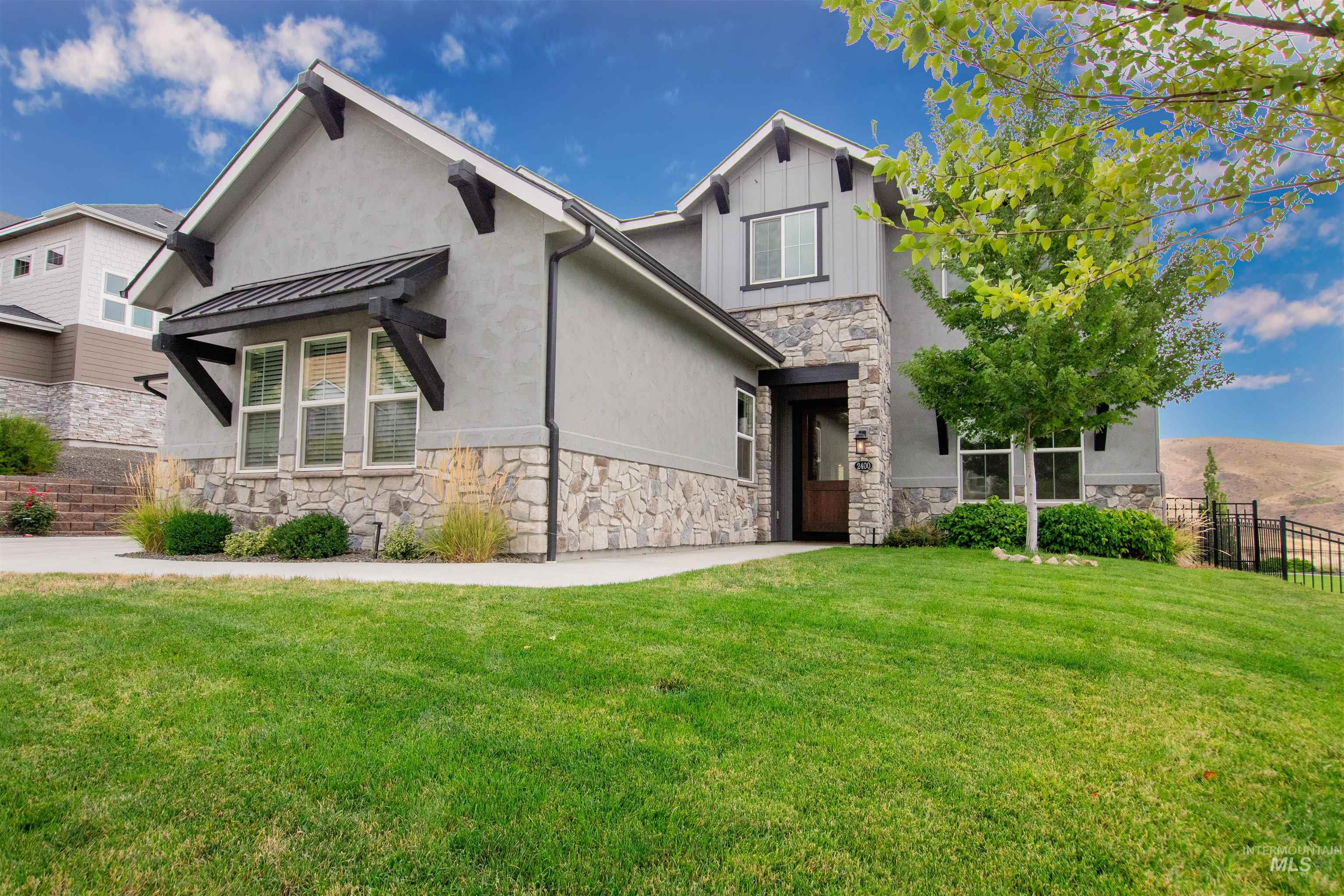 View of front of property with stone siding, a standing seam roof, a metal roof, and stucco siding