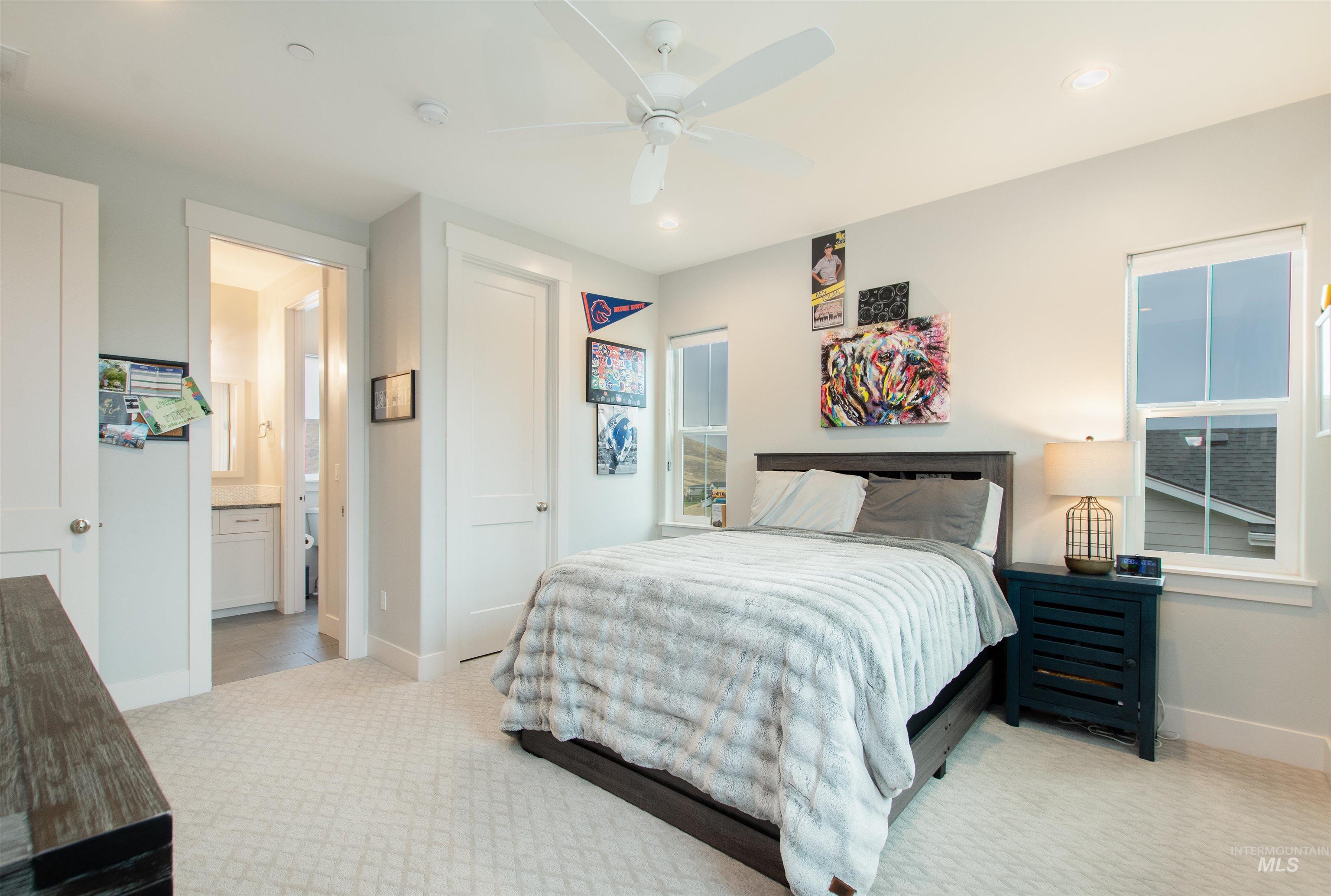Bedroom featuring light carpet, ceiling fan, recessed lighting, multiple windows, and ensuite bath
