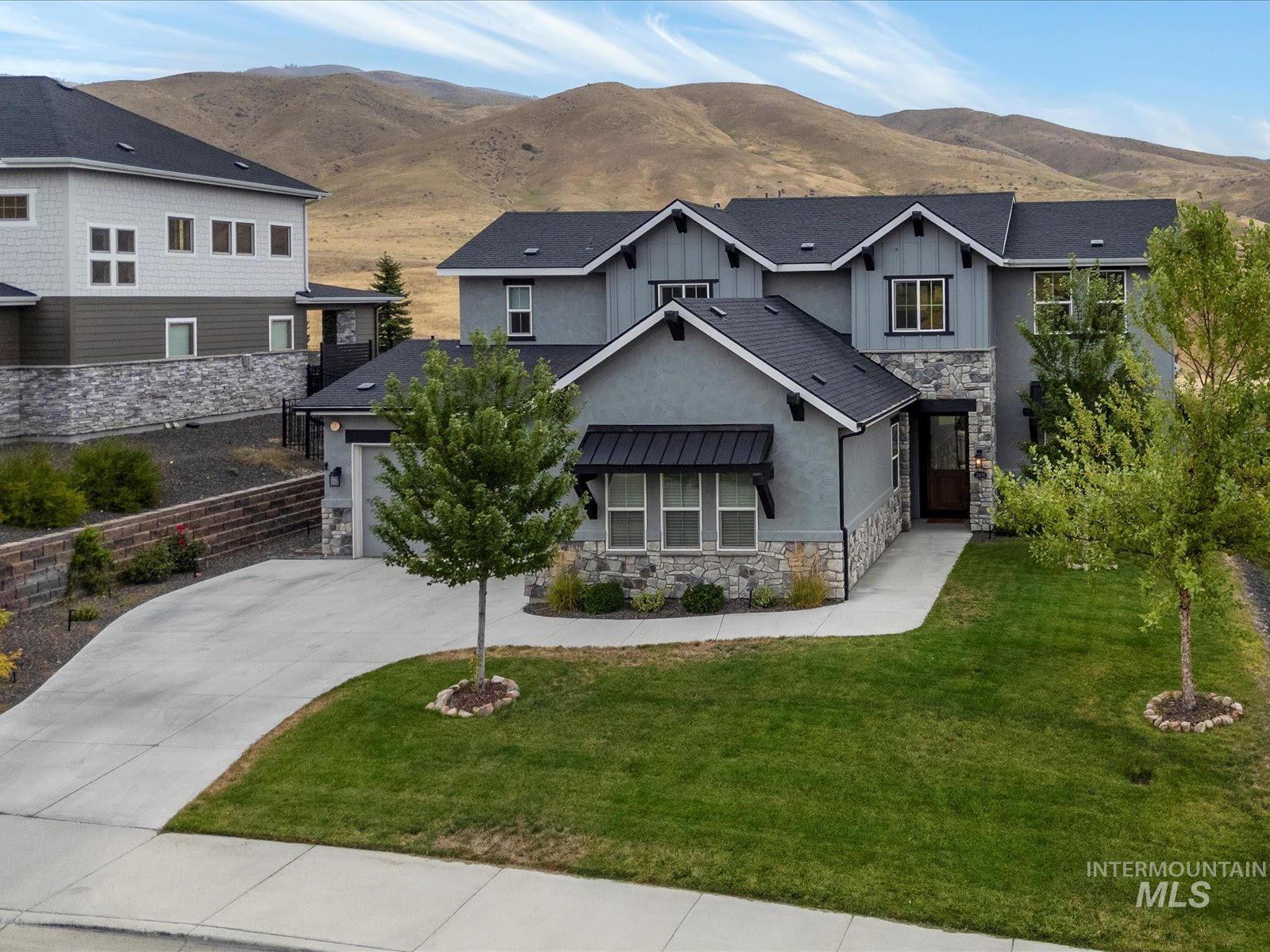 View of front of property with stone siding, driveway, a mountain view, and a front yard