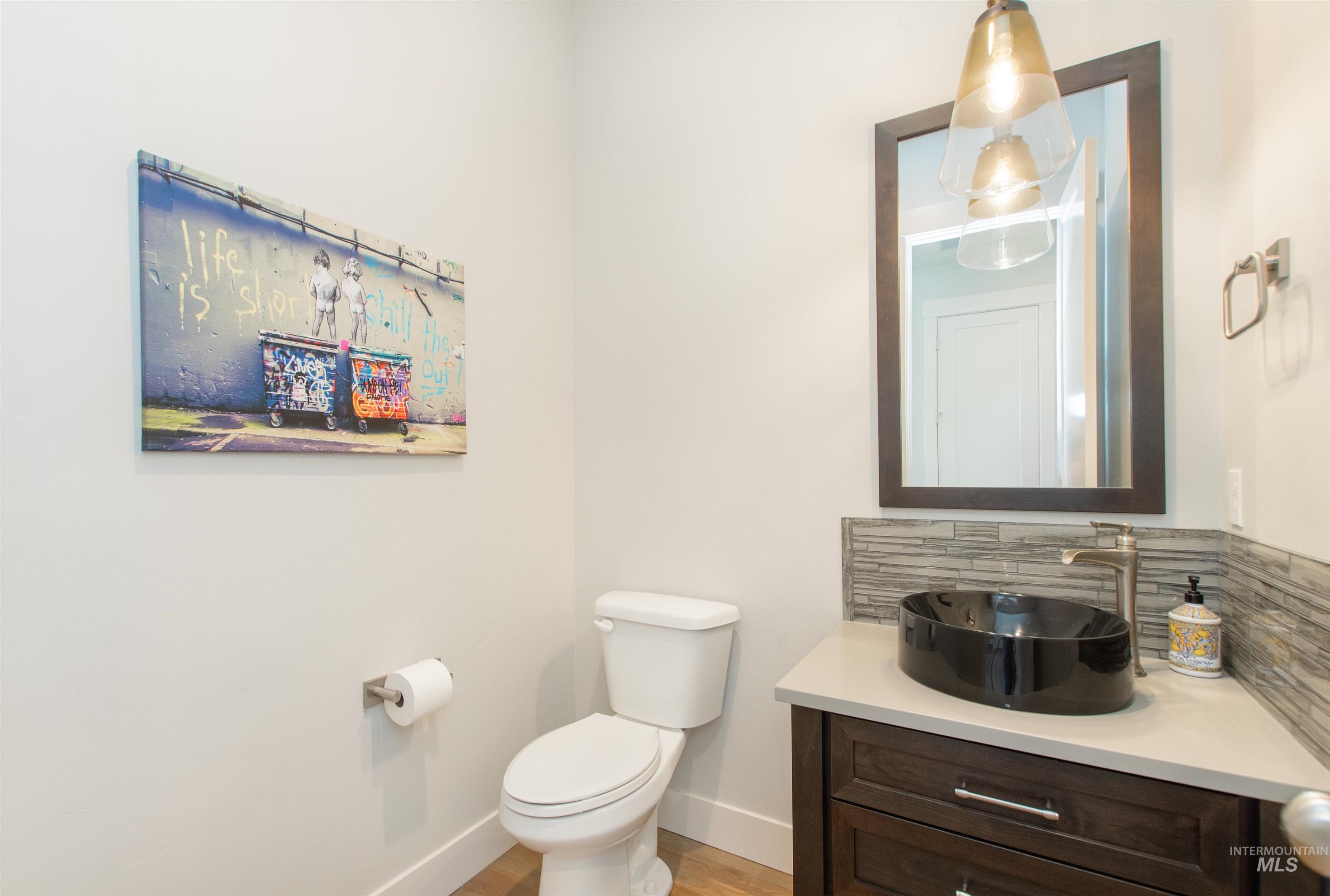 Half bathroom with vanity, tasteful backsplash, and light wood-type flooring