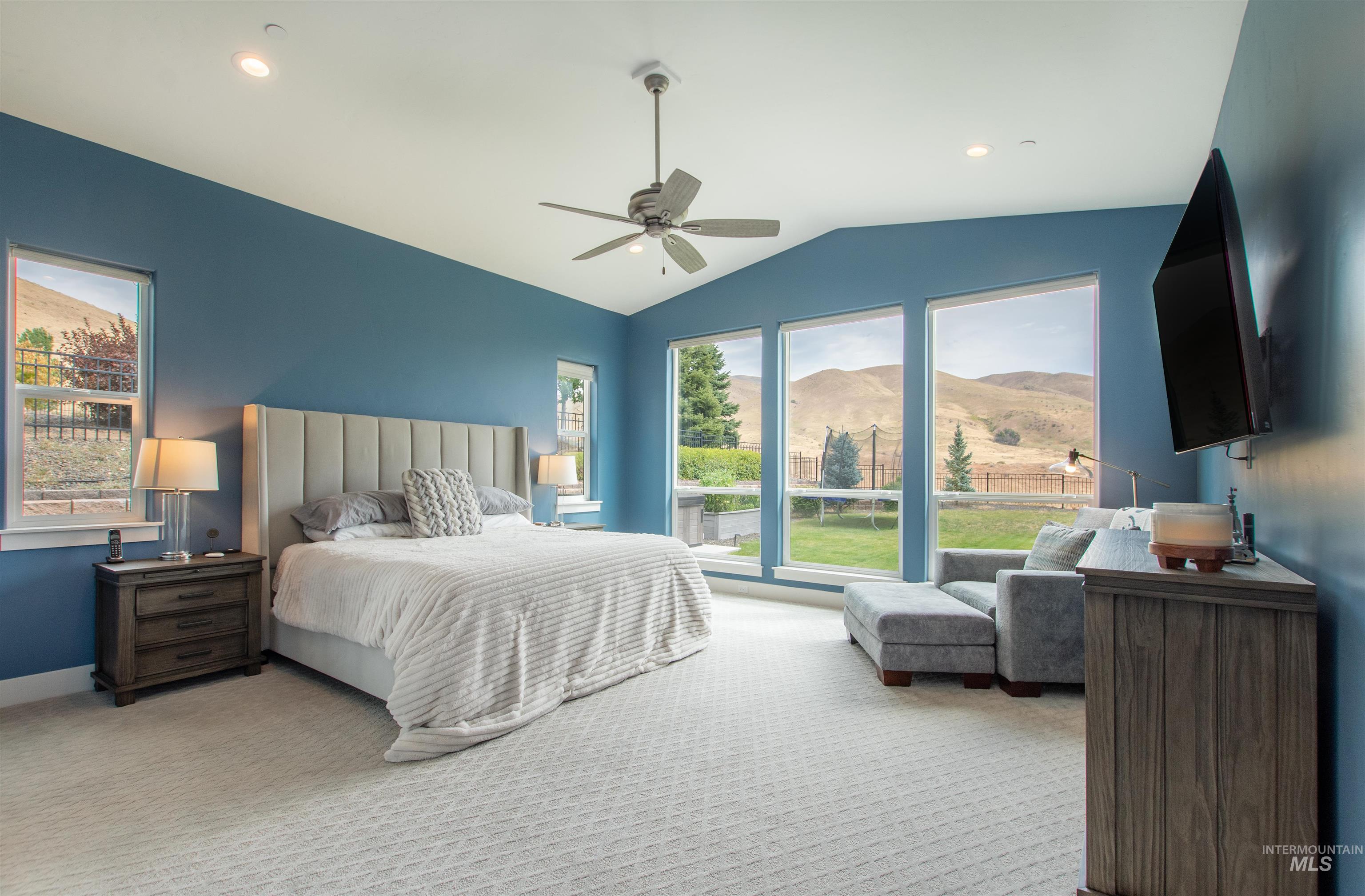Carpeted bedroom featuring multiple windows, vaulted ceiling, a ceiling fan, and recessed lighting