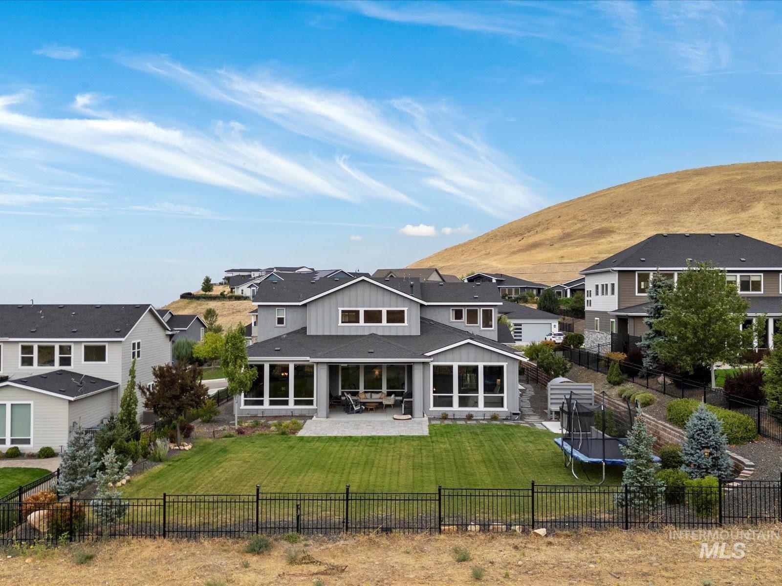 Rear view of property with a patio, a trampoline, a fenced backyard, a mountain view, and board and batten siding