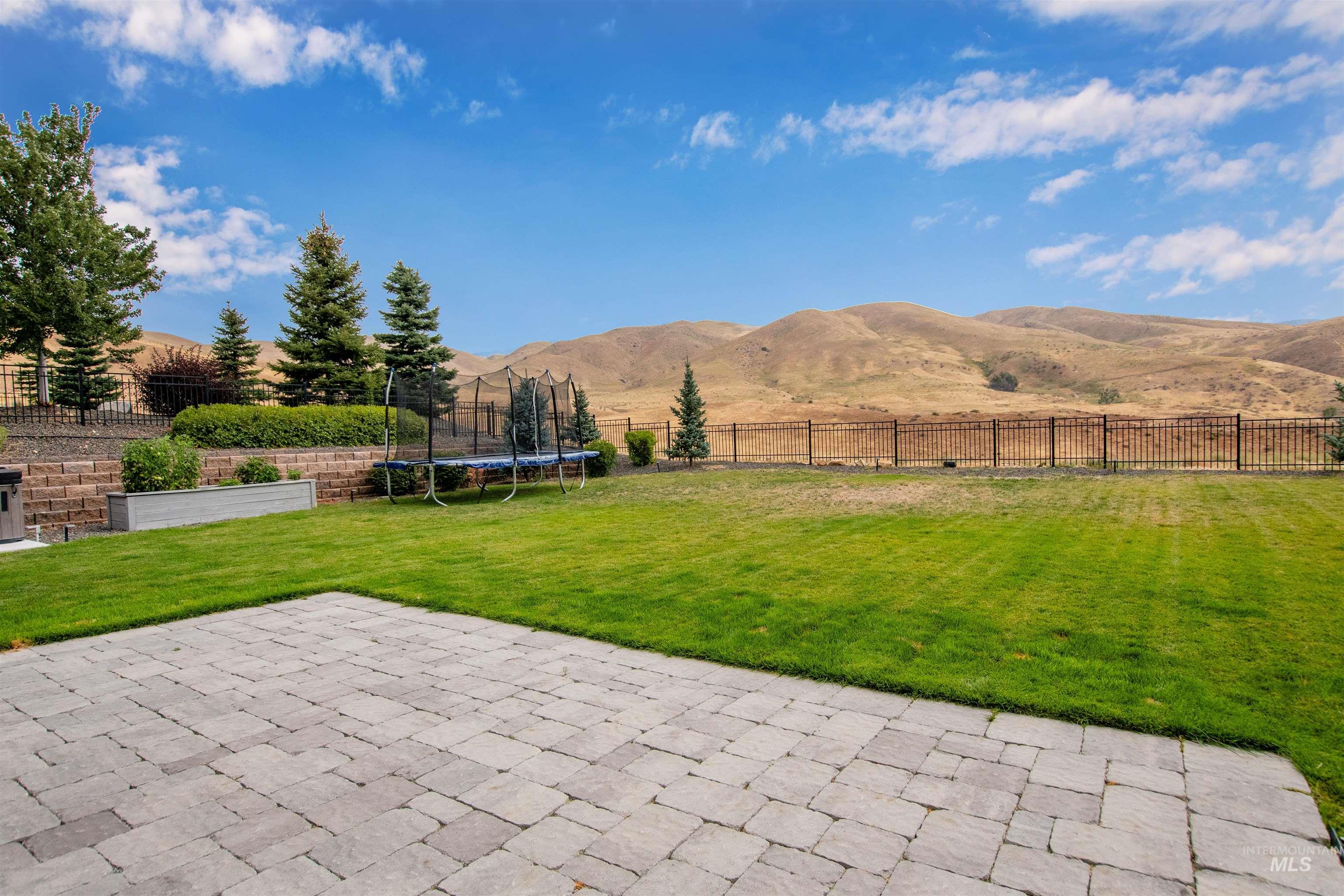 Fenced backyard with a patio, a trampoline, and a mountain view