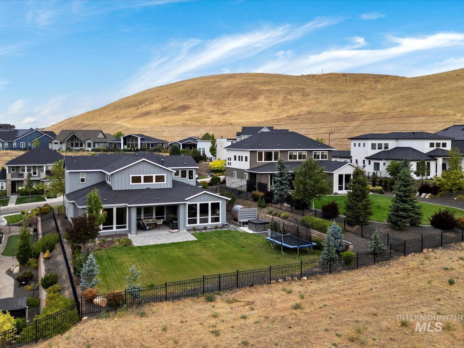 Back of house with a patio area, a fenced backyard, a trampoline, and a mountain view