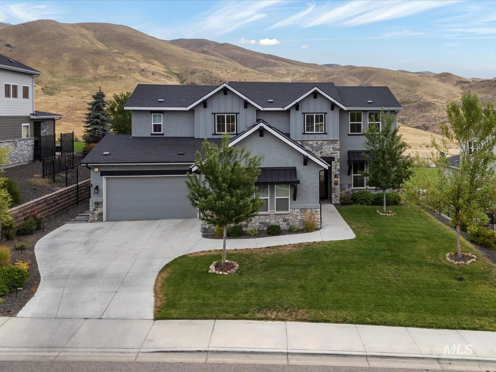 View of front facade featuring stone siding, concrete driveway, a mountain view, and a shingled roof