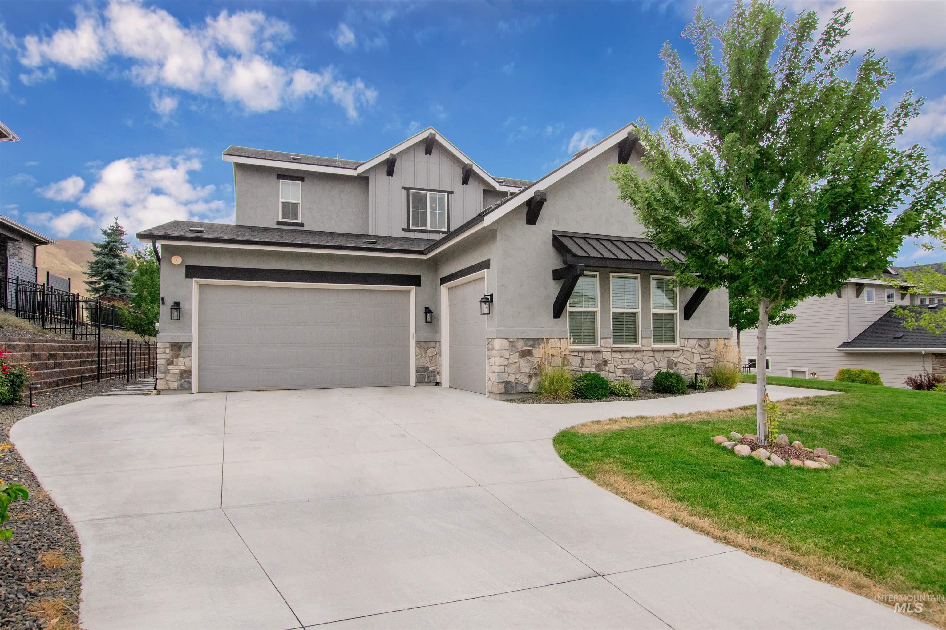View of front of house featuring a garage, stone siding, a standing seam roof, and driveway