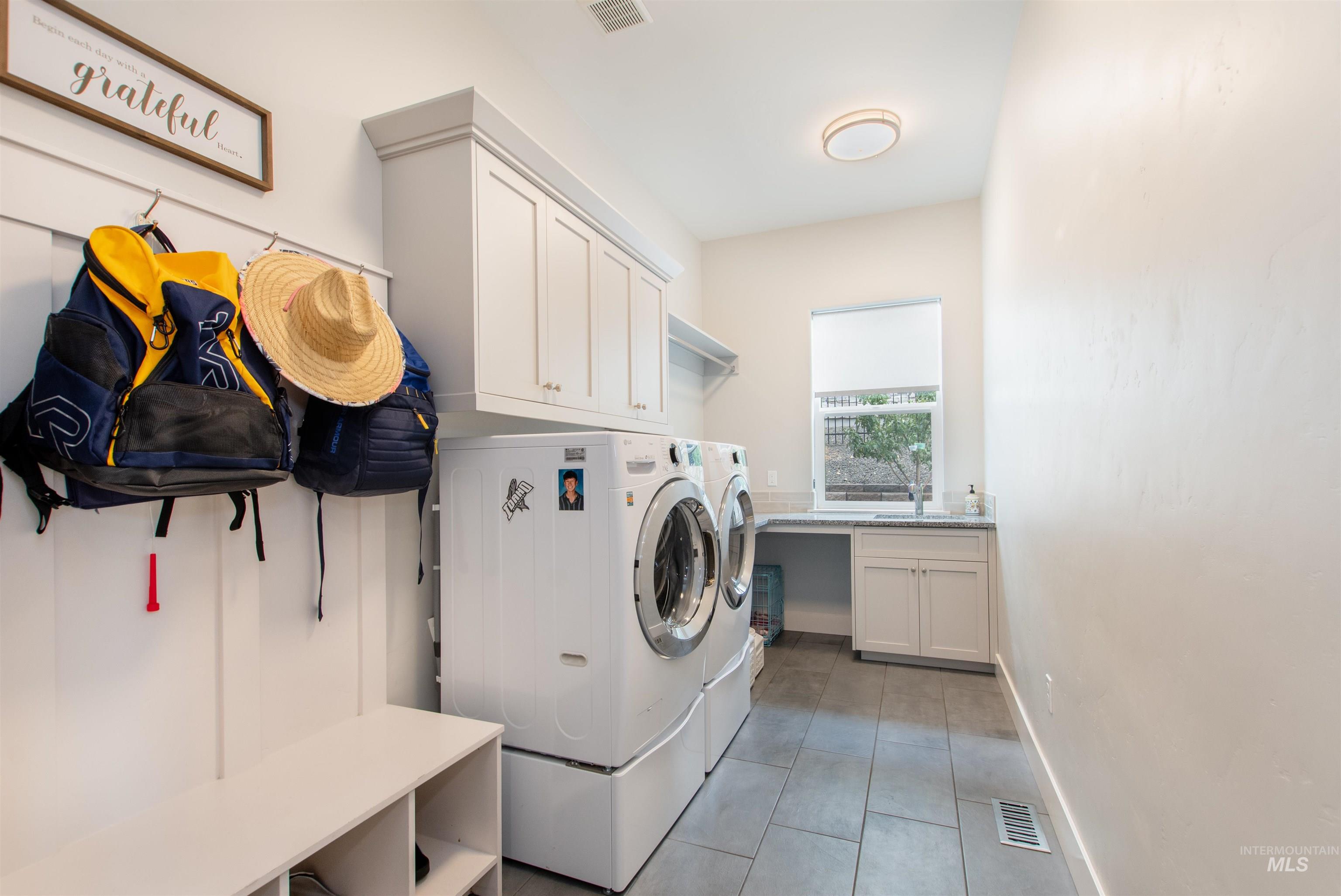 Washroom with washing machine and clothes dryer, cabinet space, and light tile patterned floors