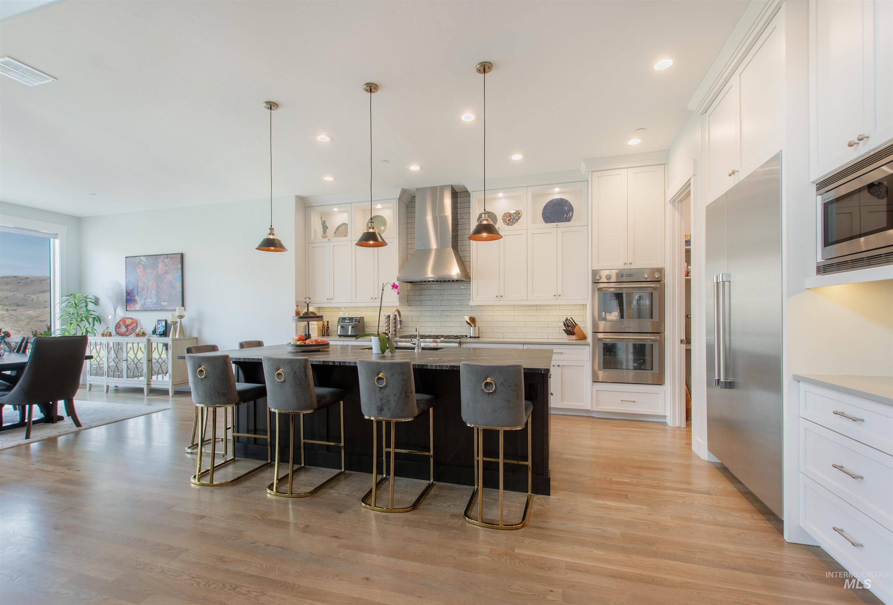 Kitchen with white cabinets, a kitchen bar, light wood-type flooring, and recessed lighting