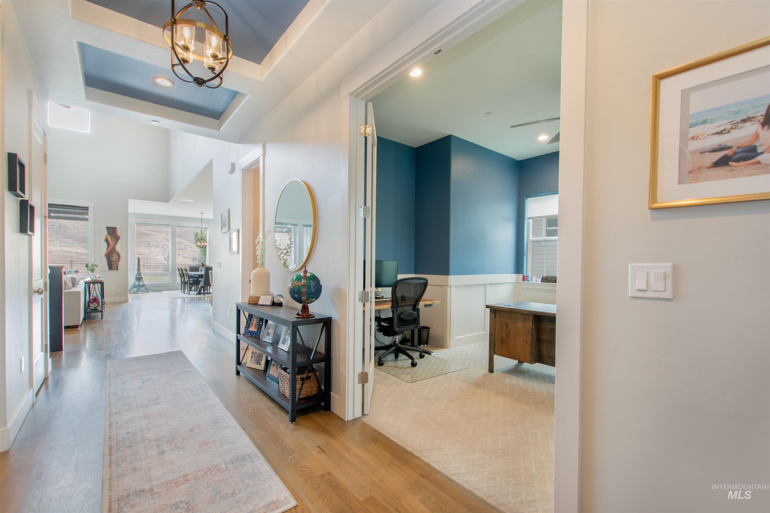 Hallway with a desk, light wood-style flooring, a chandelier, recessed lighting, and a raised ceiling