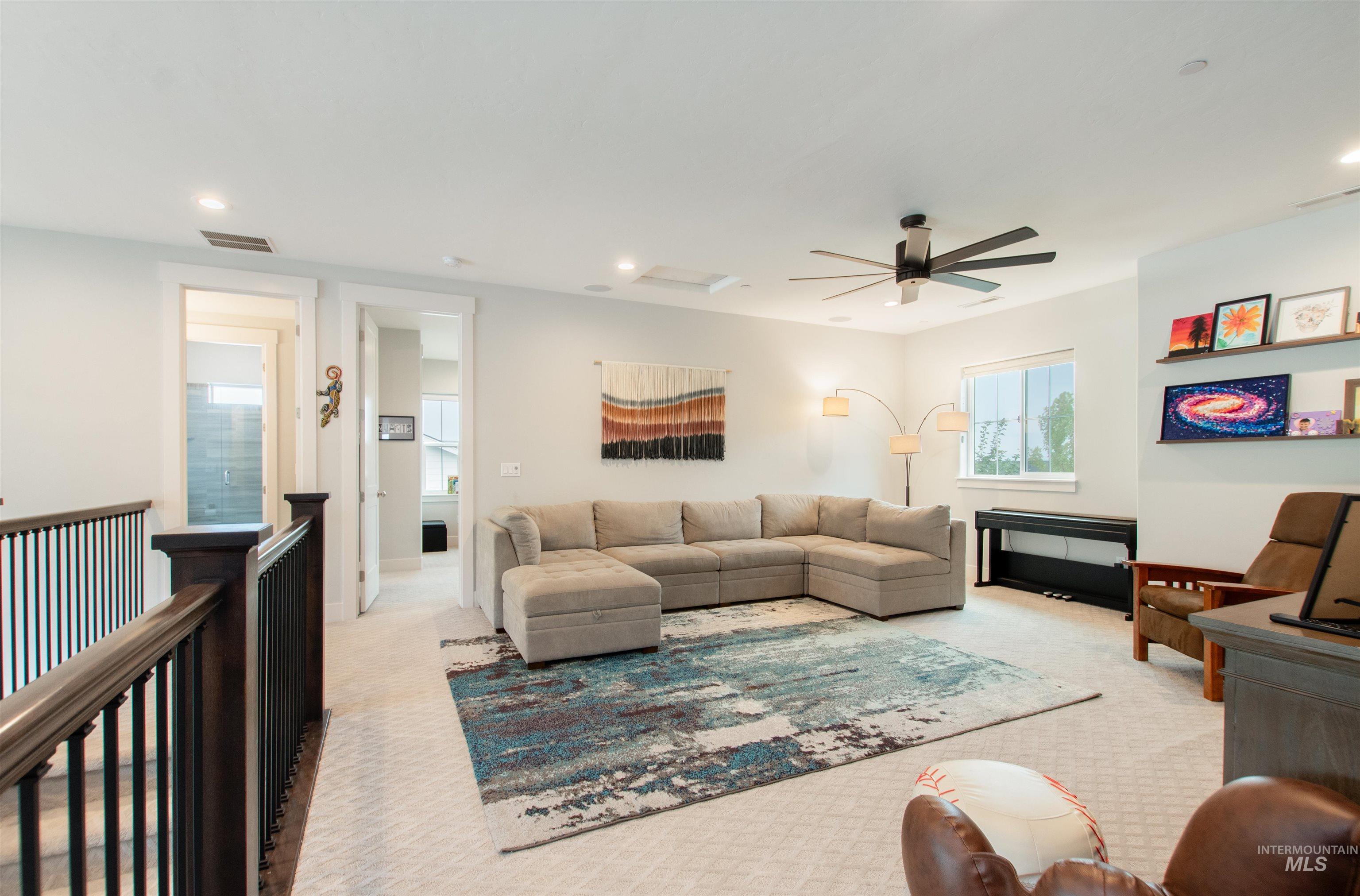 Carpeted living area featuring recessed lighting, ceiling fan, and attic access