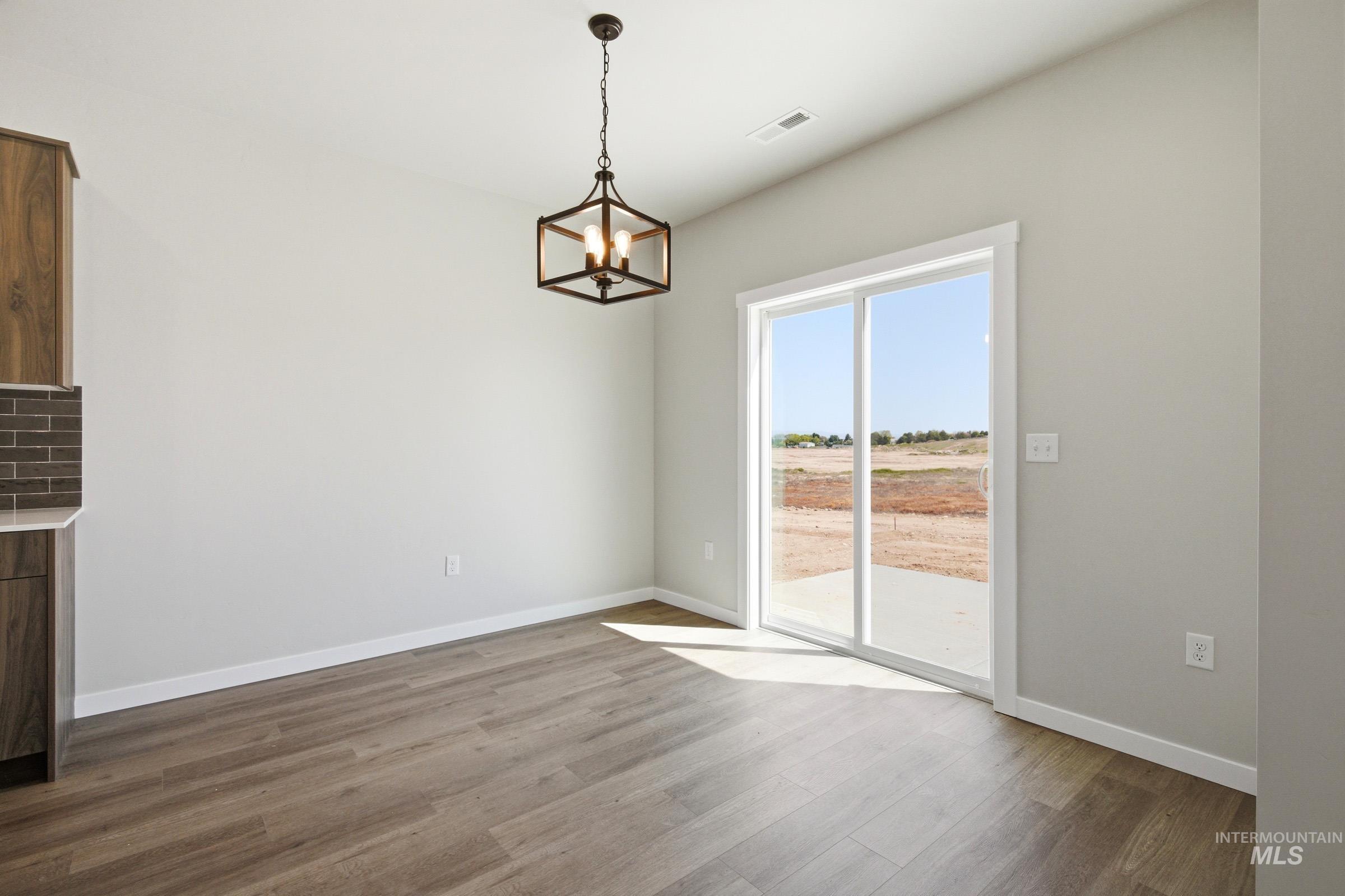 Dining area featuring wood-finish flooring, light gray walls, and a modern geometric chandelier