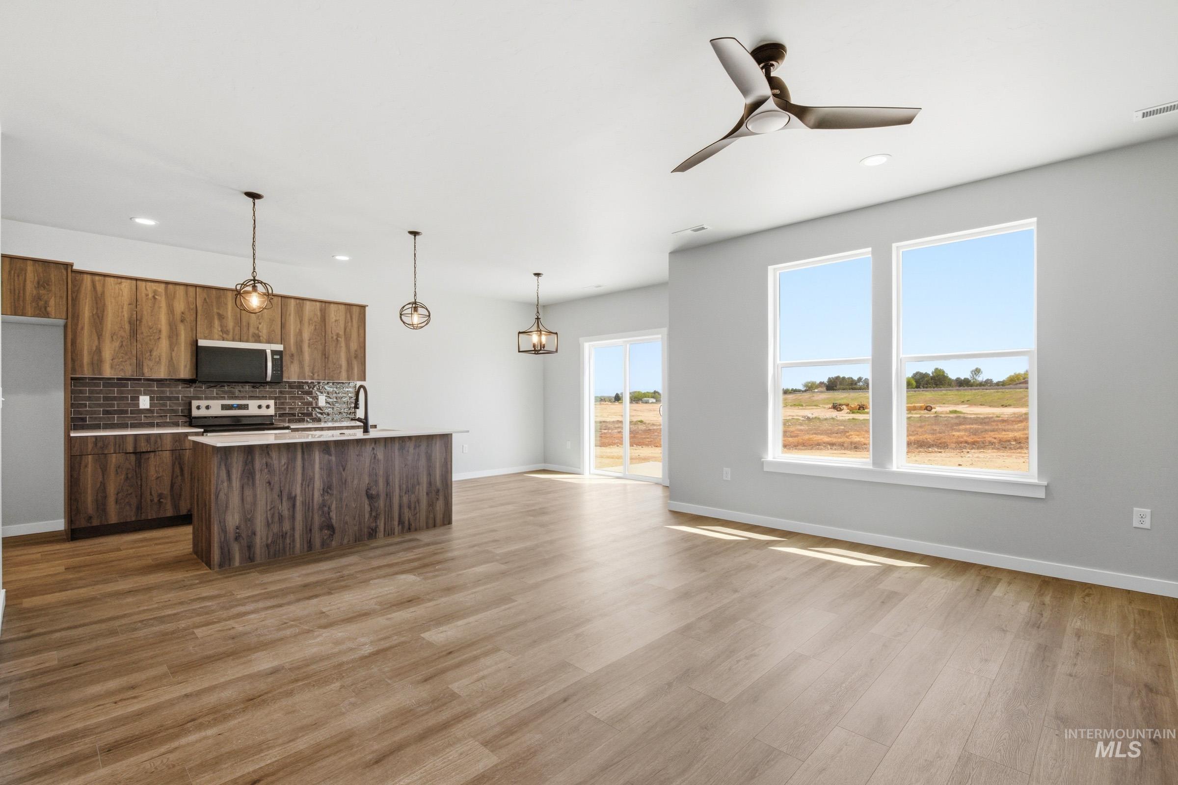 Modern kitchen featuring wood-finish cabinetry, a subway tile backsplash, and a central island with pendant lighting