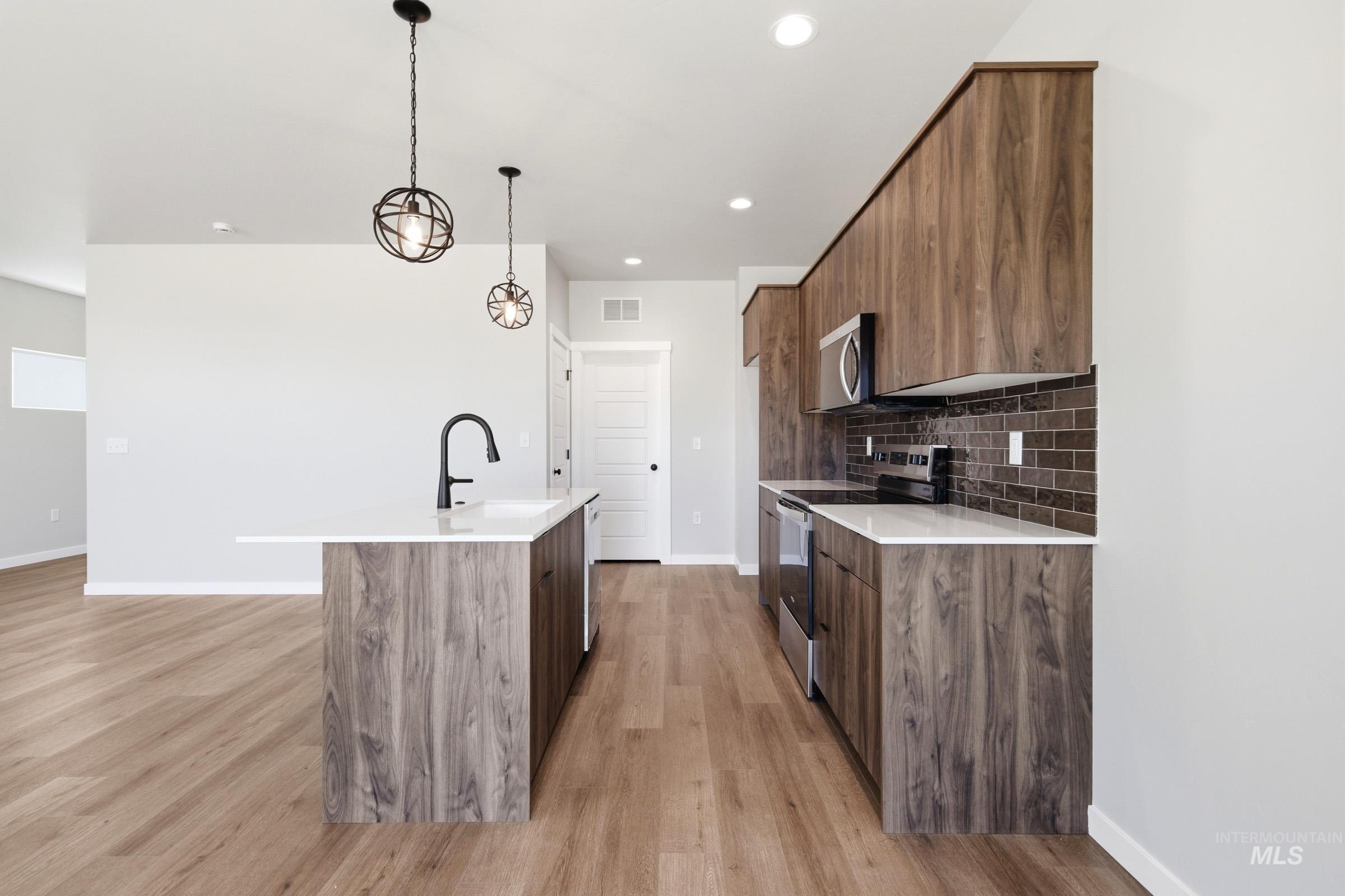 Contemporary kitchen featuring wood-finish cabinetry, white countertops, and a subway tile backsplash