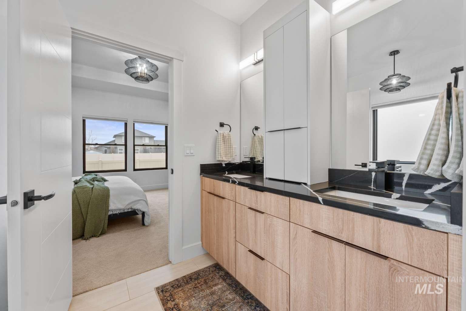 Ensuite bathroom with light colored carpet, double vanity, and light tile patterned floors