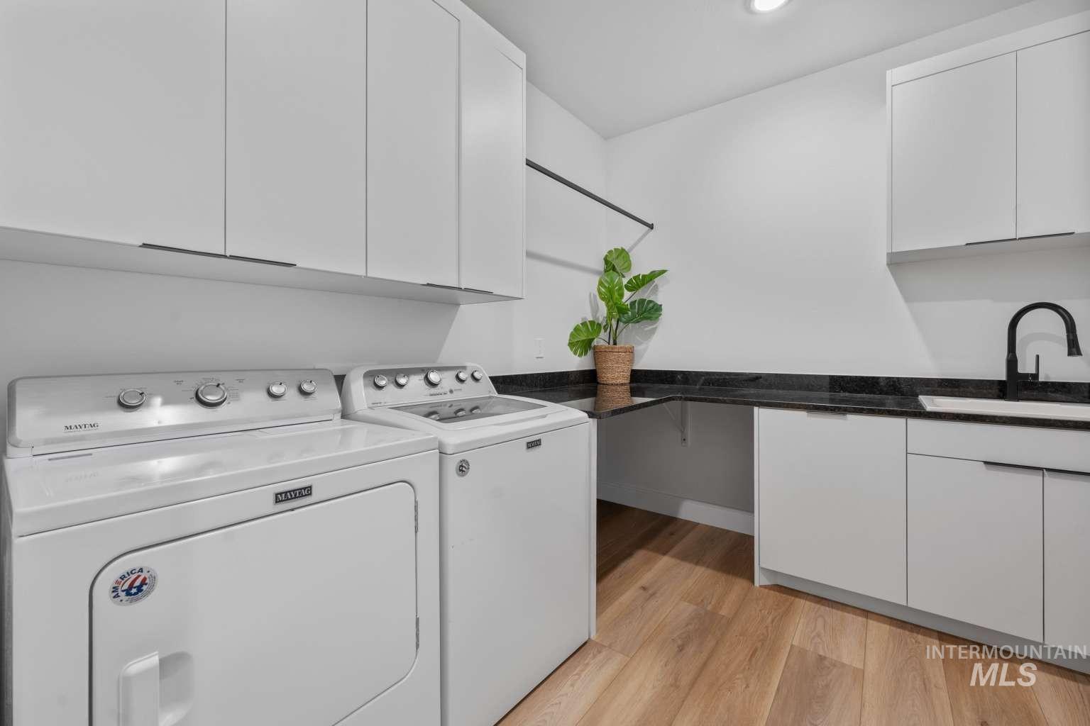 Laundry room with light wood-type flooring, washing machine and clothes dryer, cabinet space, and recessed lighting