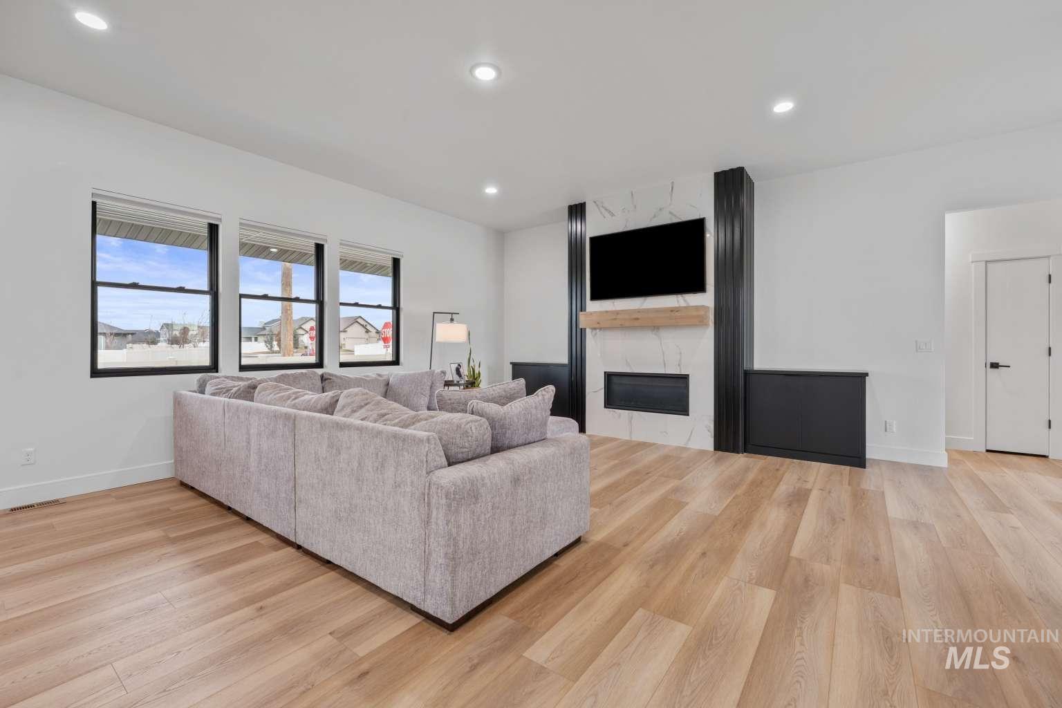 Living room with light wood-type flooring, a premium fireplace, and recessed lighting