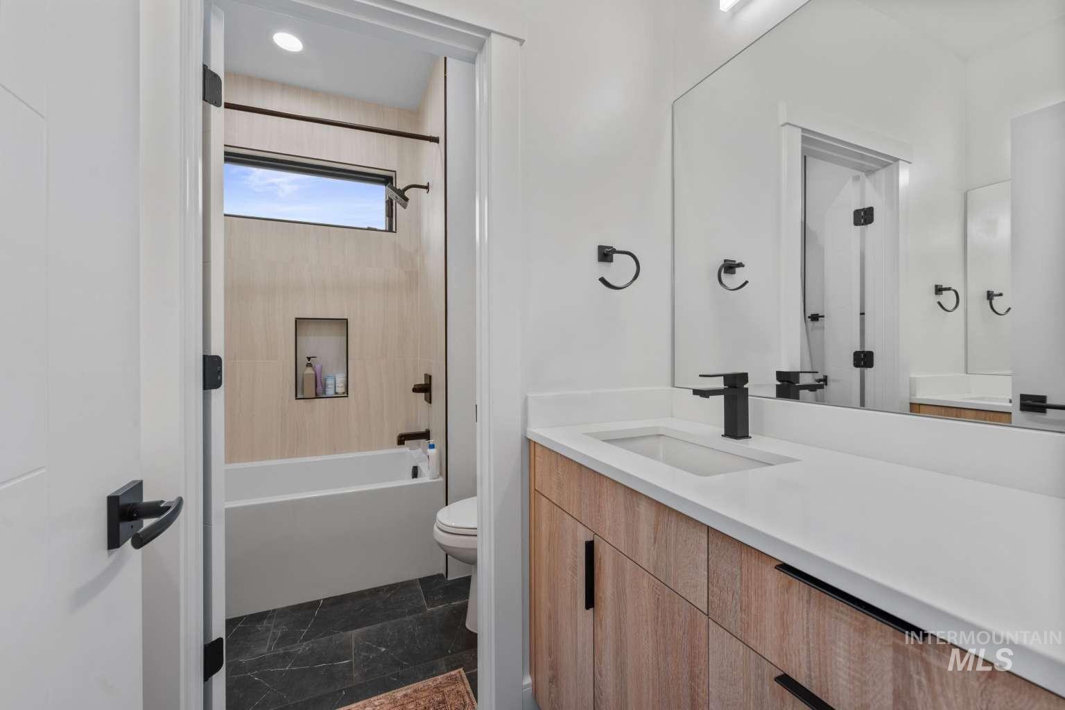 Full bath featuring shower / tub combination, vanity, and stone tile floors