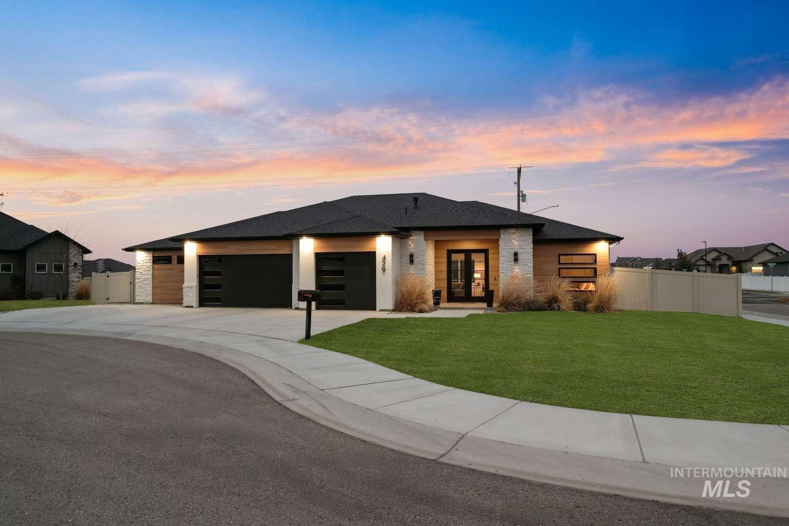 View of front facade featuring an attached garage, french doors, driveway, and roof with shingles