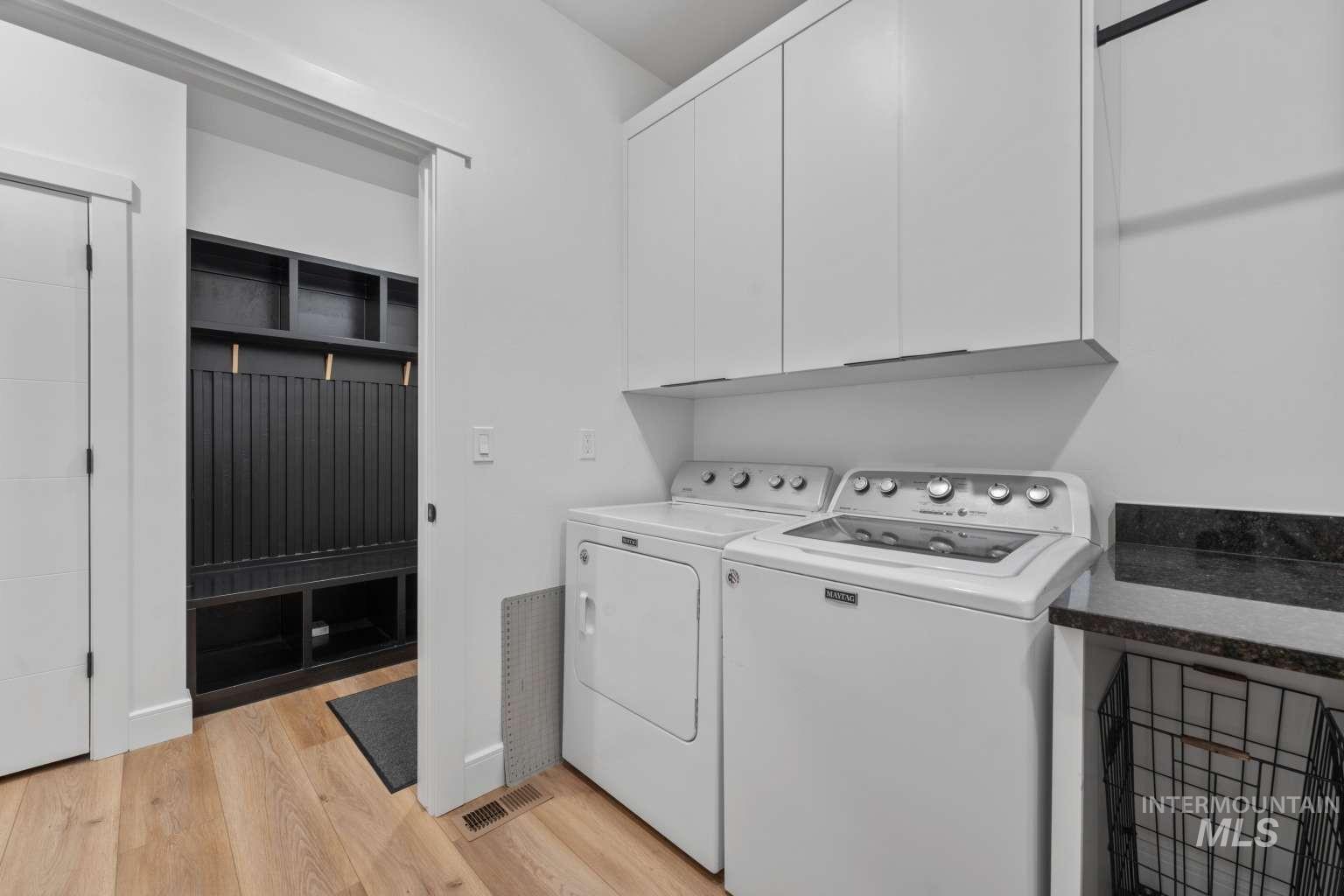 Laundry room with cabinet space, light wood-type flooring, and washing machine and dryer