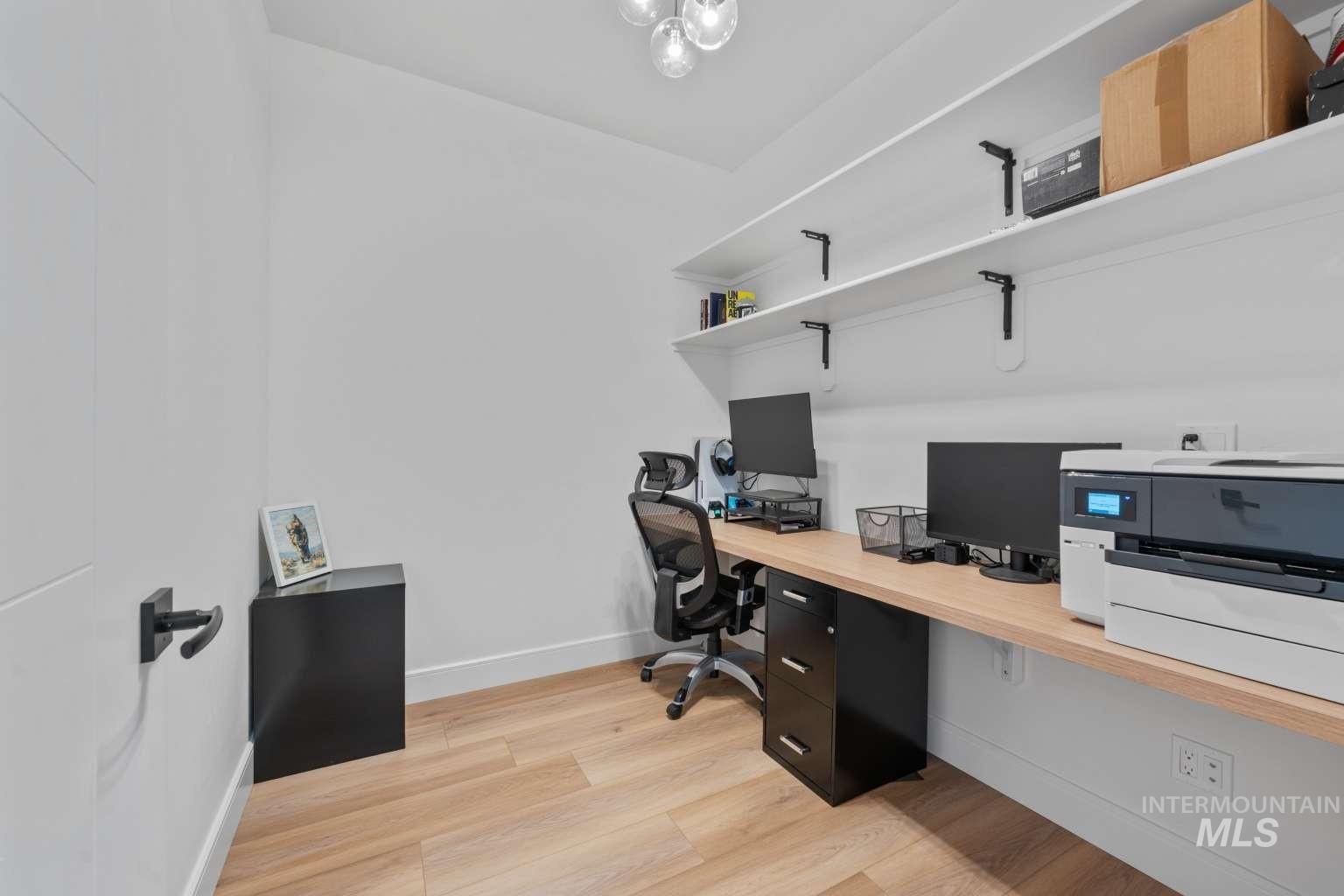 Home office featuring light wood finished floors and built in study area