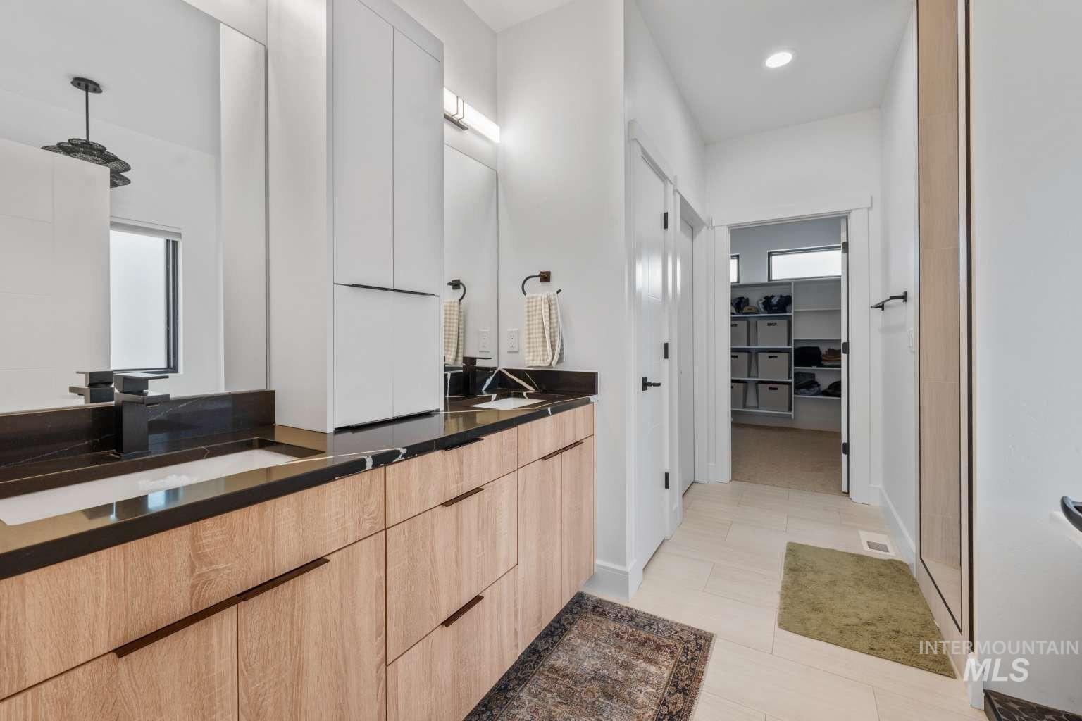 Full bath featuring double vanity, a spacious closet, a shower, and recessed lighting