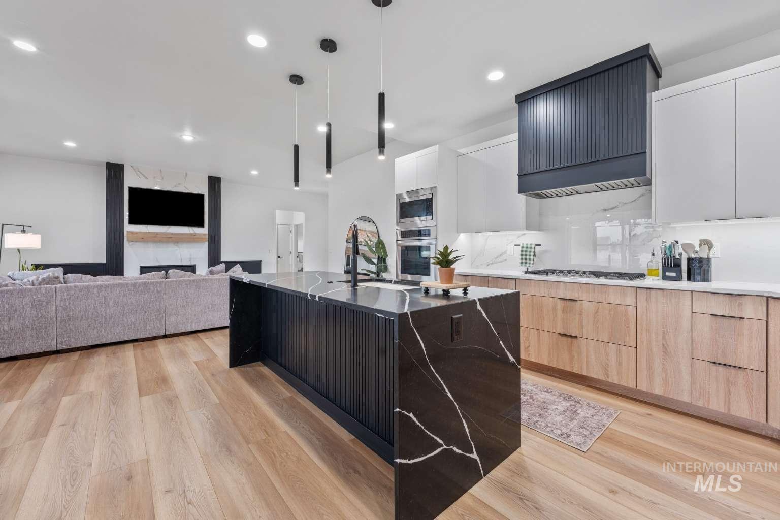 Two tone kitchen with dual tone cabinets, pendant lighting, modern cabinets, dark stone counters, and light wood finished floors
