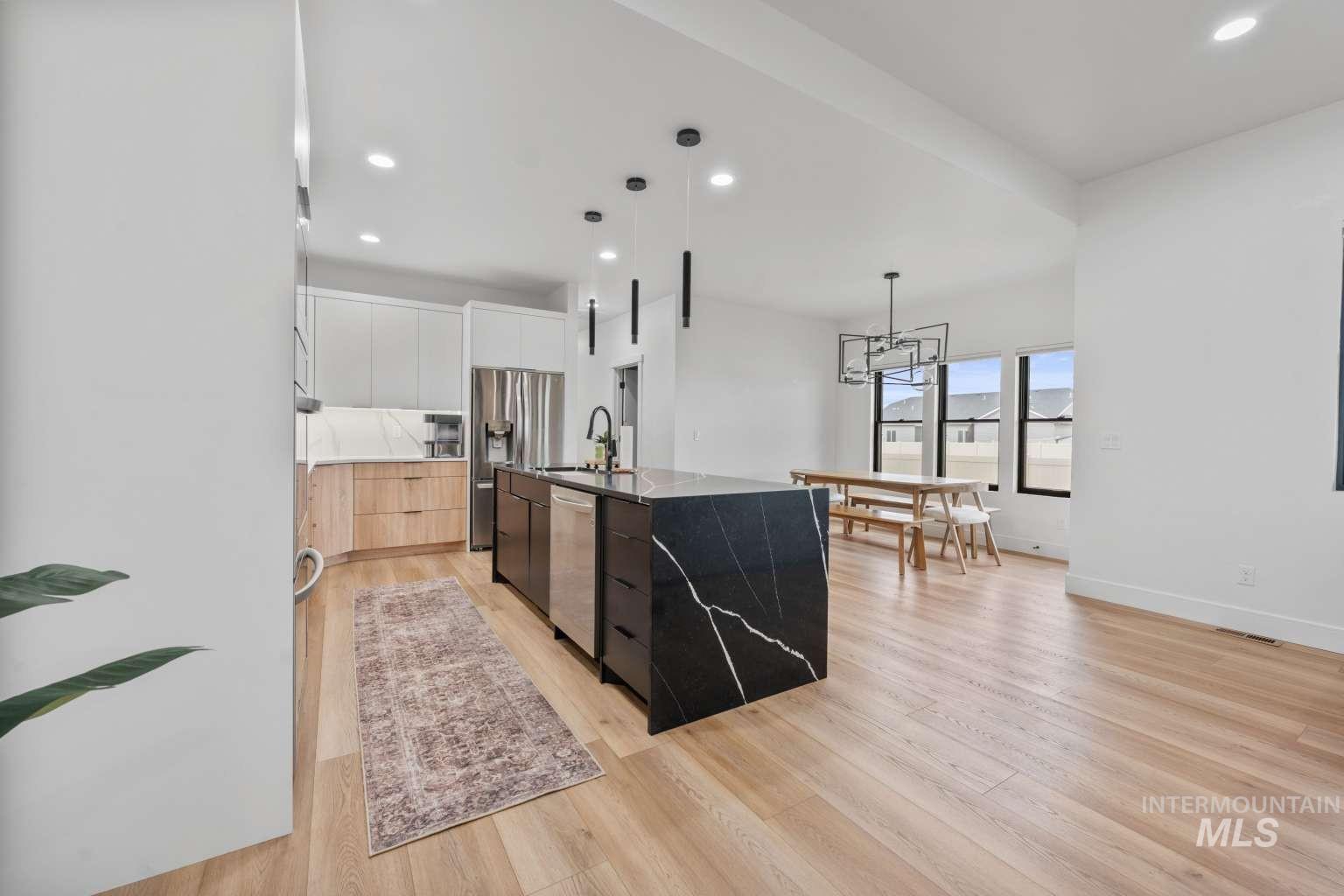 Dual tone kitchen featuring dual tone cabinets, modern cabinets, hanging light fixtures, stainless steel appliances, and dark stone counters