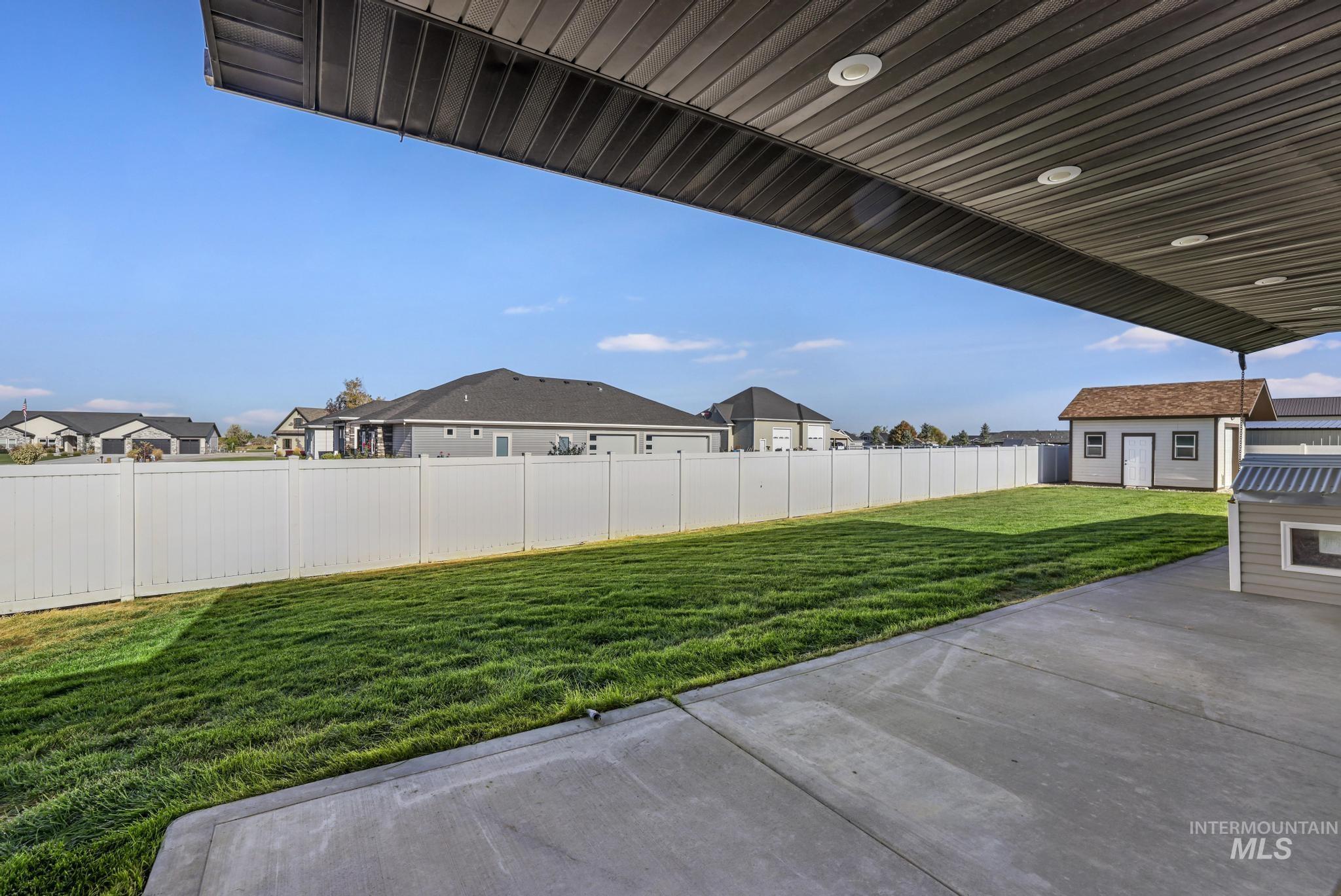 Fenced backyard featuring a patio area, a residential view, and an outbuilding