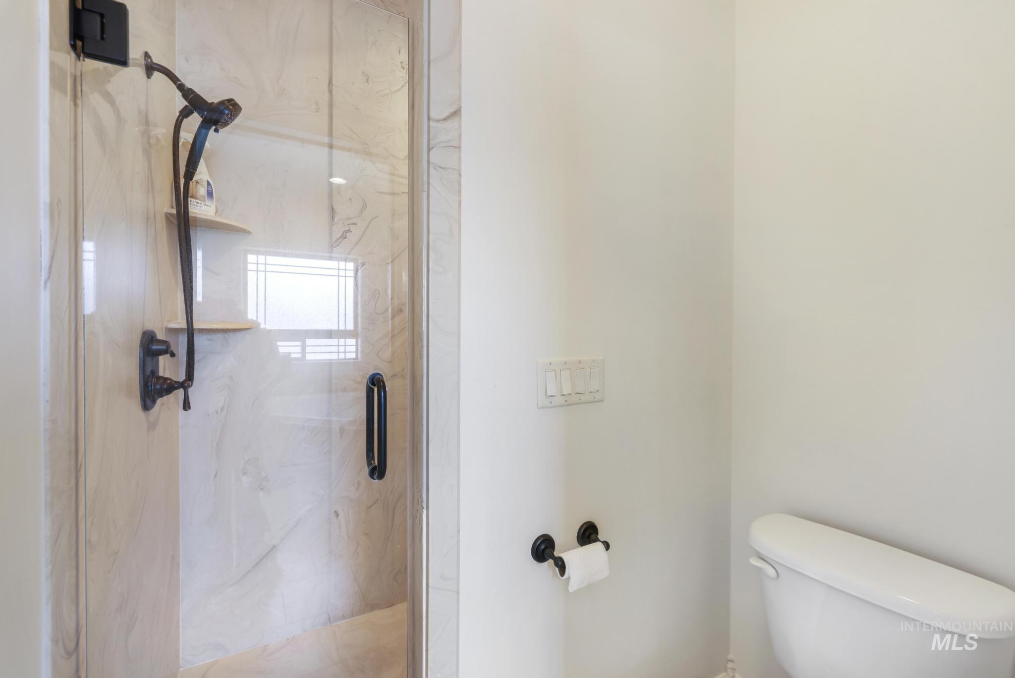 Full bathroom featuring toilet and a marble finish shower