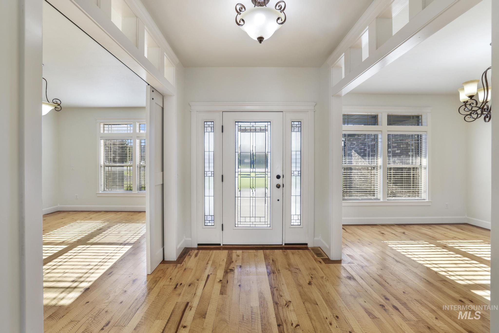 Foyer entrance with light wood-style floors and a chandelier